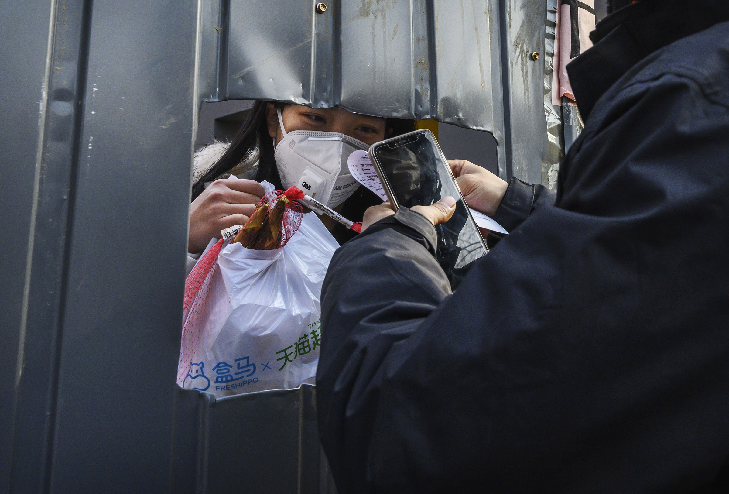 A Chinese woman wears a protective mask as she accepts a package from a courier through a cutout hole on Feb. 25, 2020 in Beijing, China. (Kevin Frayer—Getty Images)