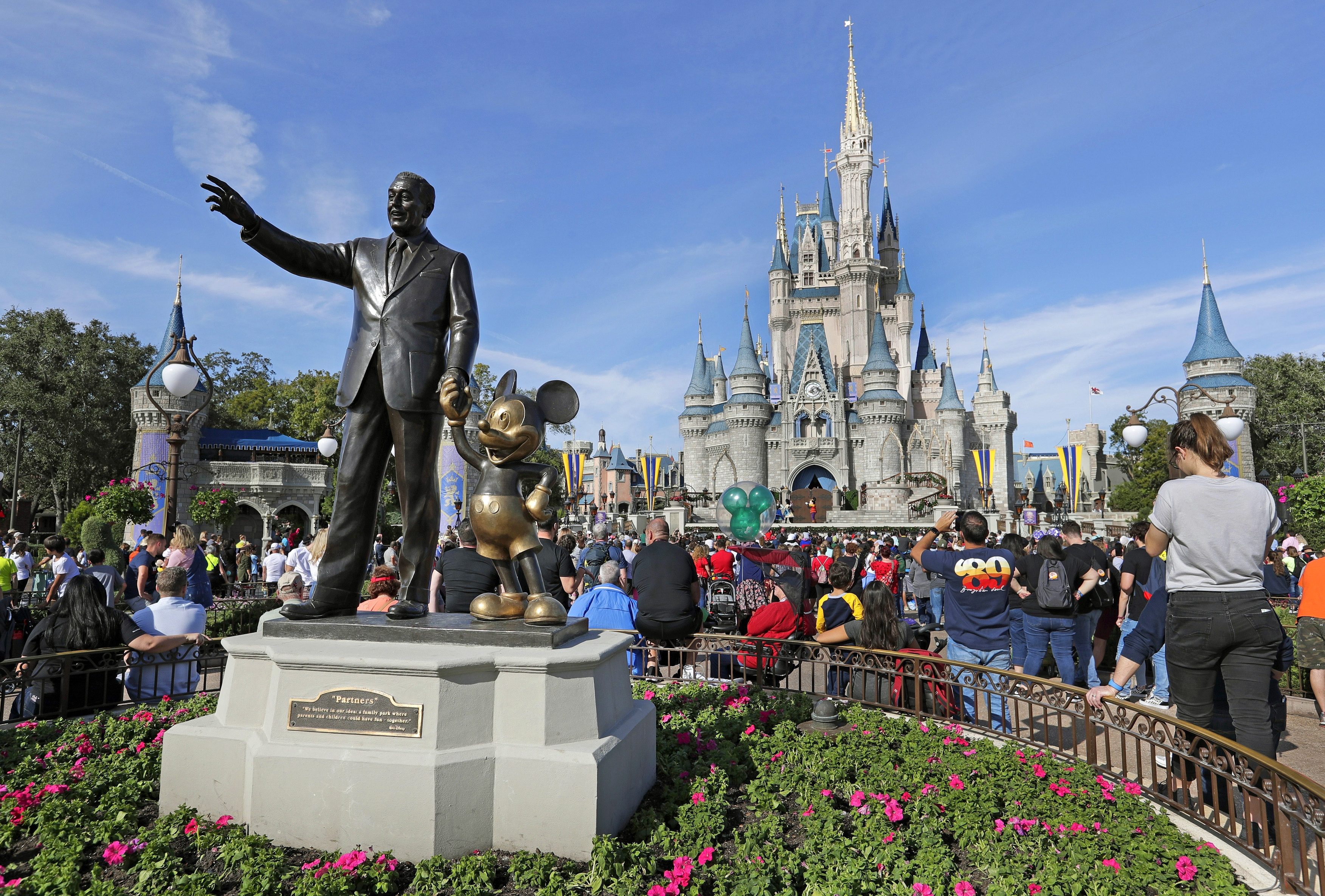 FILE - In this Jan. 9, 2019 photo, guests watch a show near a statue of Walt Disney and Micky Mouse in front of the Cinderella Castle at the Magic Kingdom at Walt Disney World in Lake Buena Vista, Fla. Disney. (John Raoux — AP)