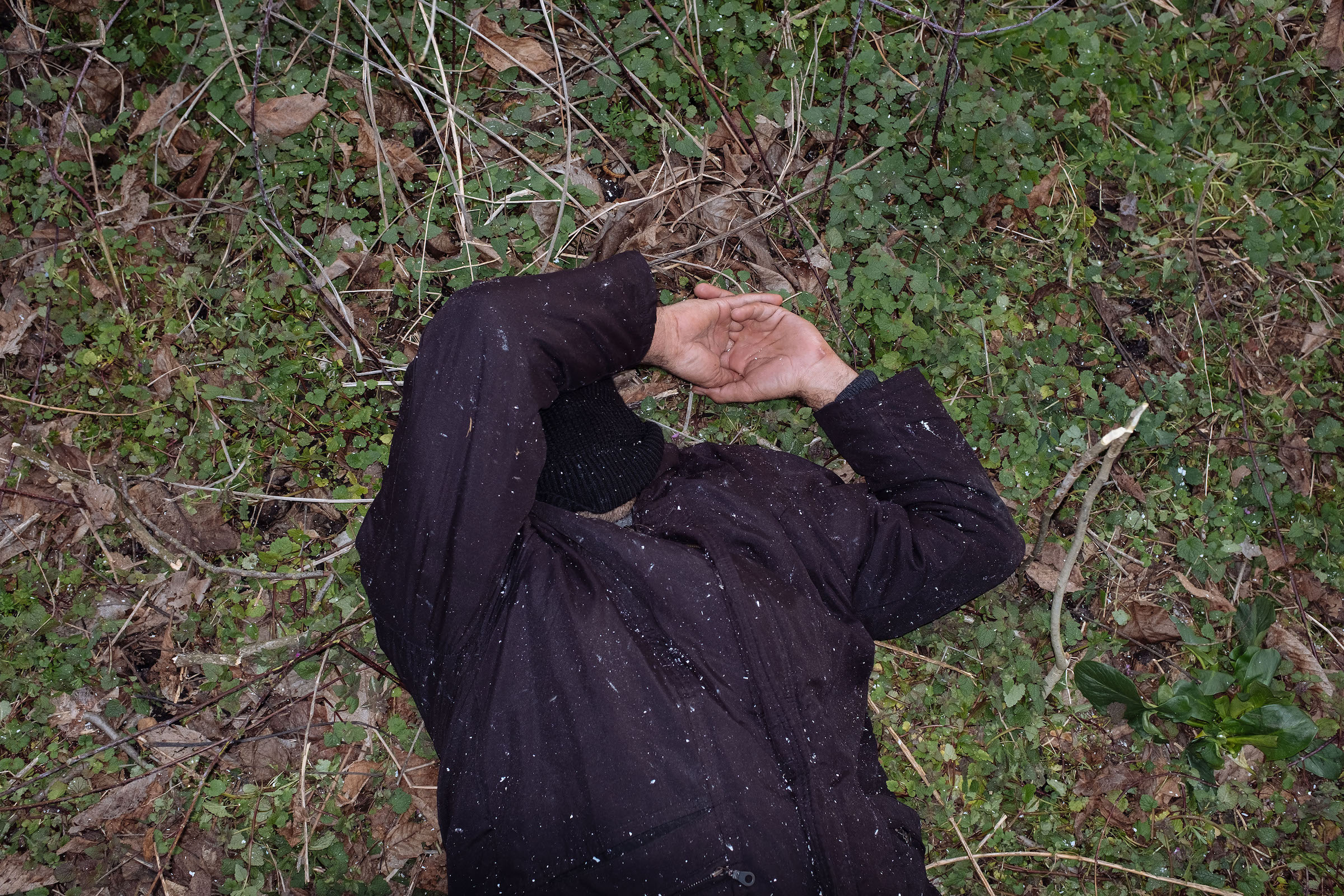 A man sleeps on the ground in the buffer zone.