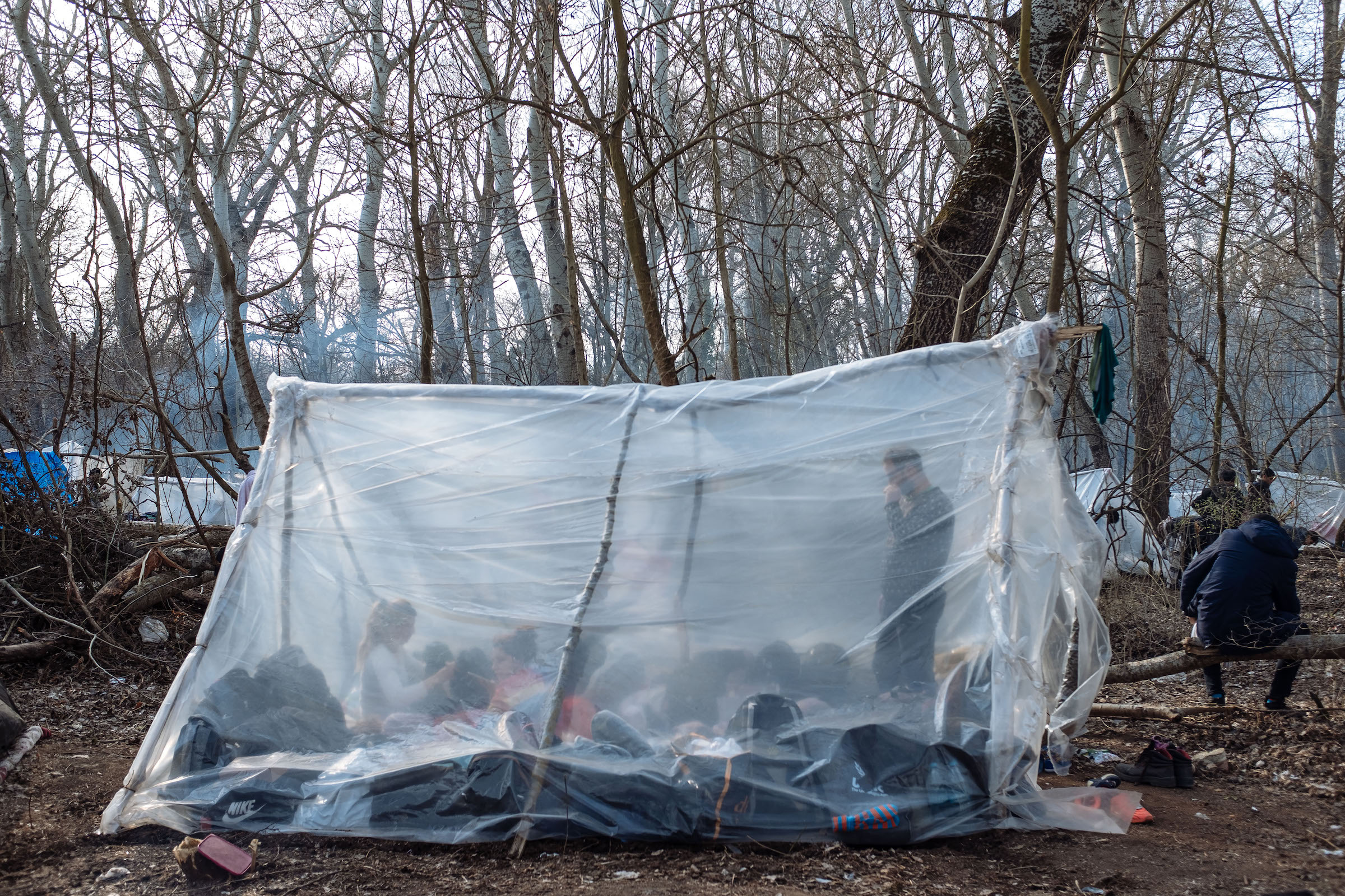 A tent made of propped-up branches, wrapped in plastic, in Edirne. Many migrants slept in the area for days, waiting for a chance to cross the border.