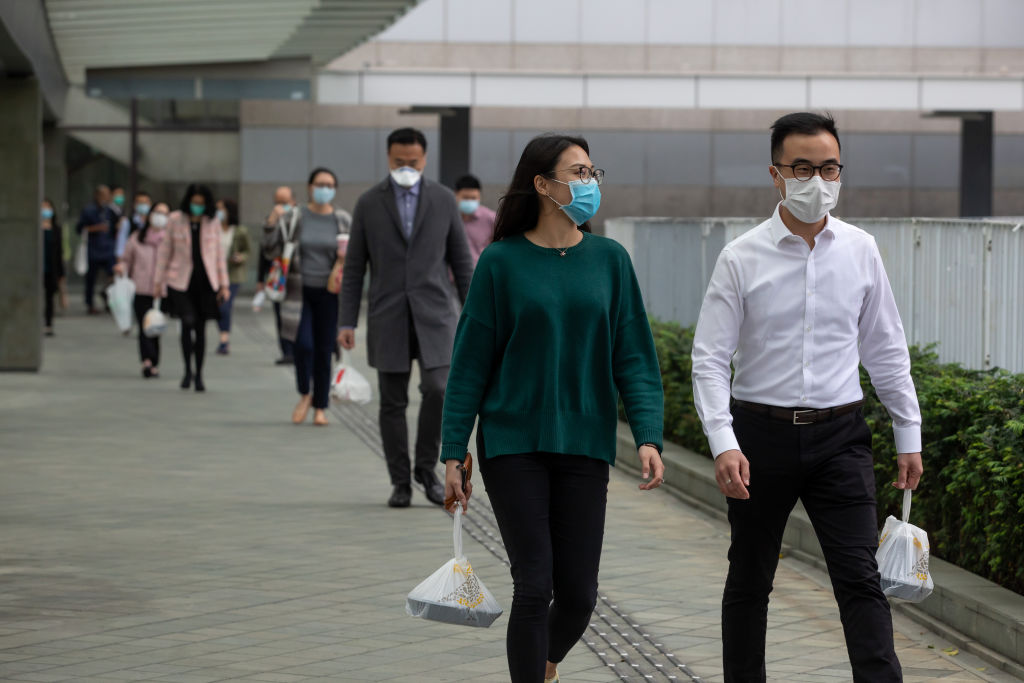 Office workers wearing masks carry take-out lunch orders while walking towards in Admiralty, Hong Kong, on Mar. 2, 2020. (Paul Yeung—Bloomberg/Getty Images)