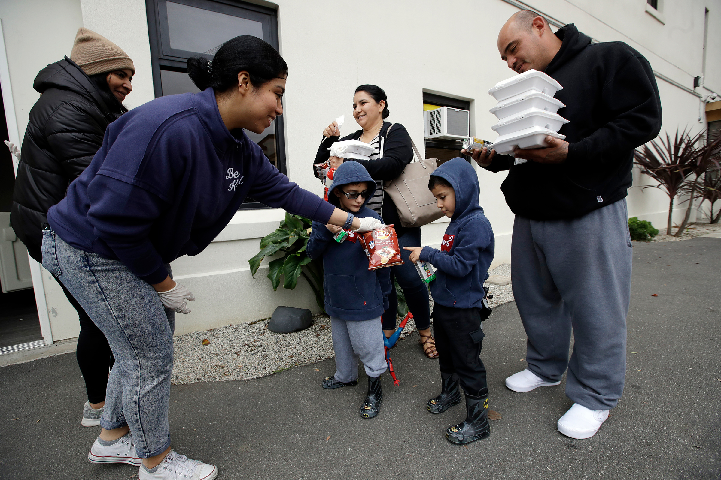 Volunteer Pahola Campos, second from left, hands out lunches to the Garcia family — mom Marie, dad Sergio, at right, and their children — on Mar. 16 at a food distribution center set up by the Dream Center for those in need due to the coronavirus outbreak in Los Angeles (Marcio Jose Sanchez—AP)