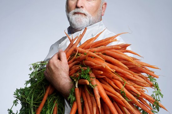 Chef José Andrés poses for a portrait while holding a large bundle of carrots