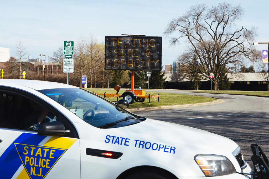 A New Jersey State Police vehicle drives in front of an electronic sign that reads "Testing Site At Capacity" outside a drive-through coronavirus testing facility at Bergen Community College in Paraumus, New Jersey, U.S., on Friday, March 20, 2020. (Angus Mordant—Bloomberg/ Getty Images)