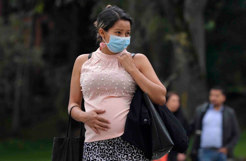 A pregnant woman wears a face mask as a preventative measure against the spread of the new coronavirus, COVID-19, as she waits for the bus in Bogota, on March 16, 2020. (RAUL ARBOLEDA/AFP via Getty Images)