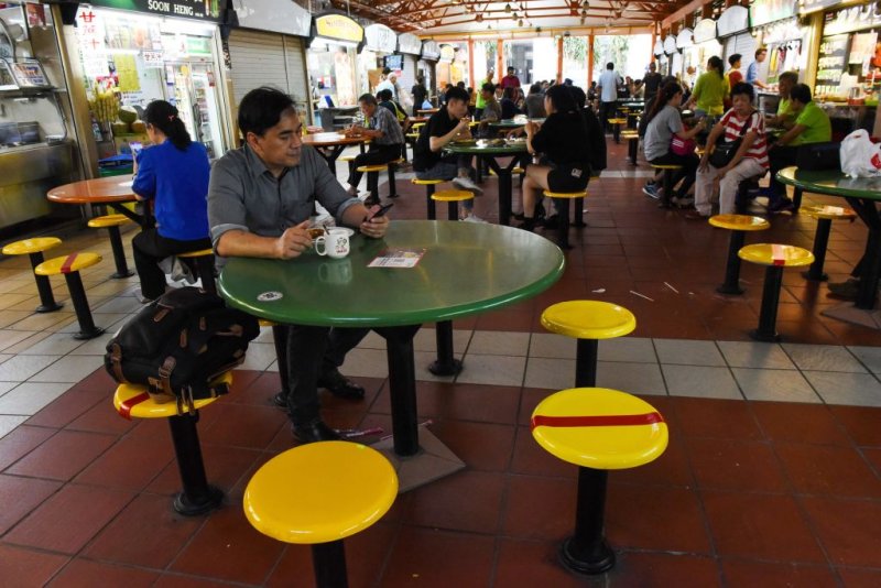 Customers take their meal while some chairs are marked with red tapes as authorities implement social distancing at a hawker centre, amid fears about the spread of the COVID-19 novel coronavirus in Singapore on March 18, 2020.