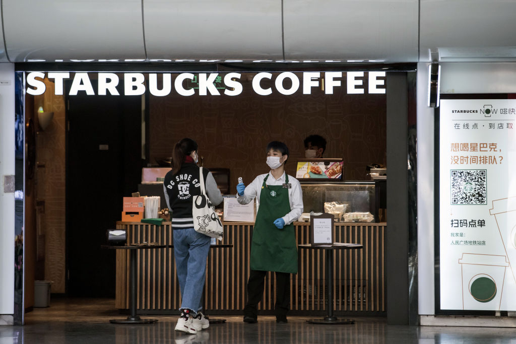 An employee checks the temperature of a customer at the entrance of a Starbucks Corp. coffee shop in Shanghai, China on March 2, 2020. (Qilai Shen&mdash;Bloomberg/Getty Images)