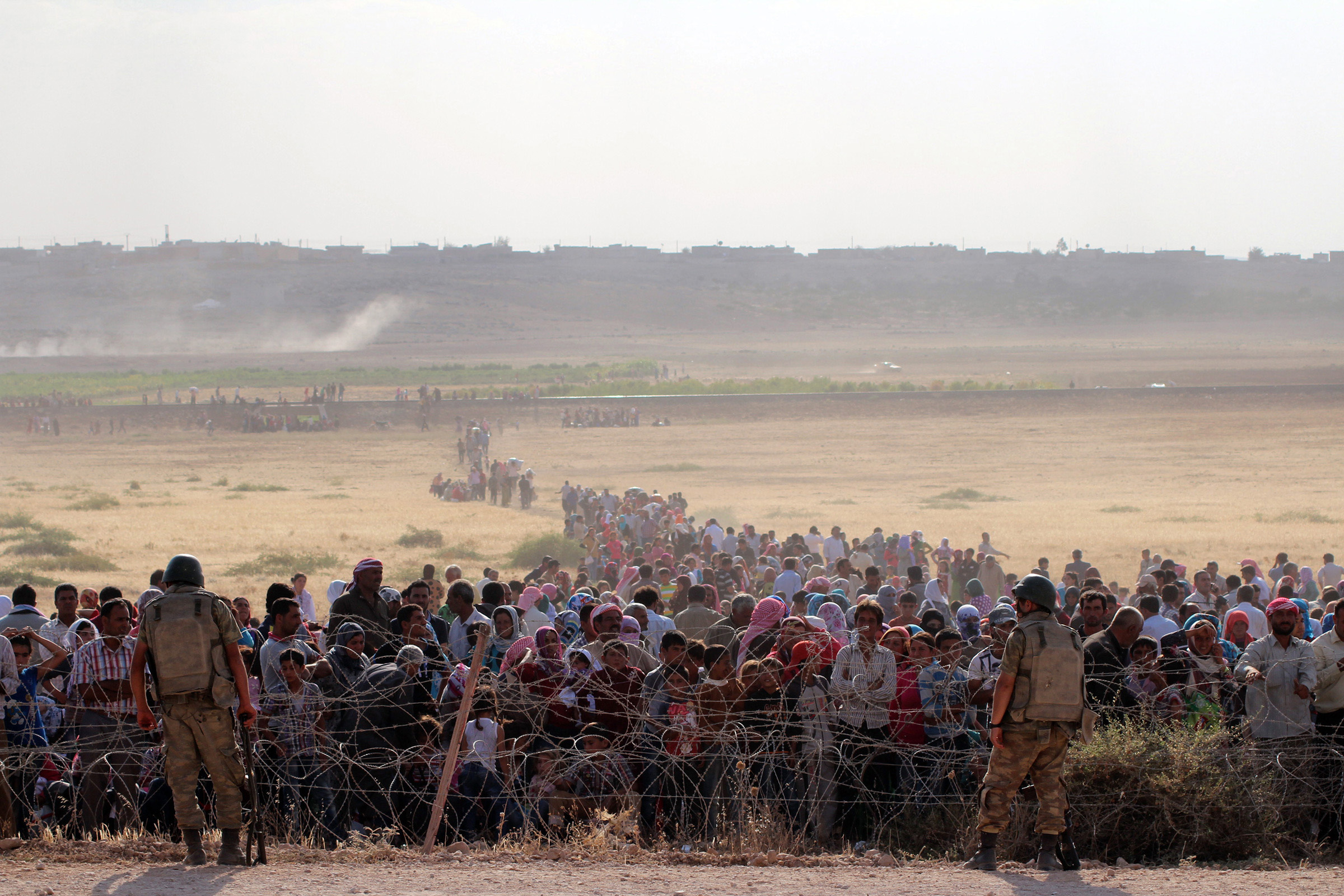 Syrians fleeing from clashes between the Islamic State of Iraq and Syria (ISIS) militants wait at the Turkish-Syrian border to cross into Turkey on Sept. 18, 2014. (Halil Fidan—Anadolu Agency/Getty Images)