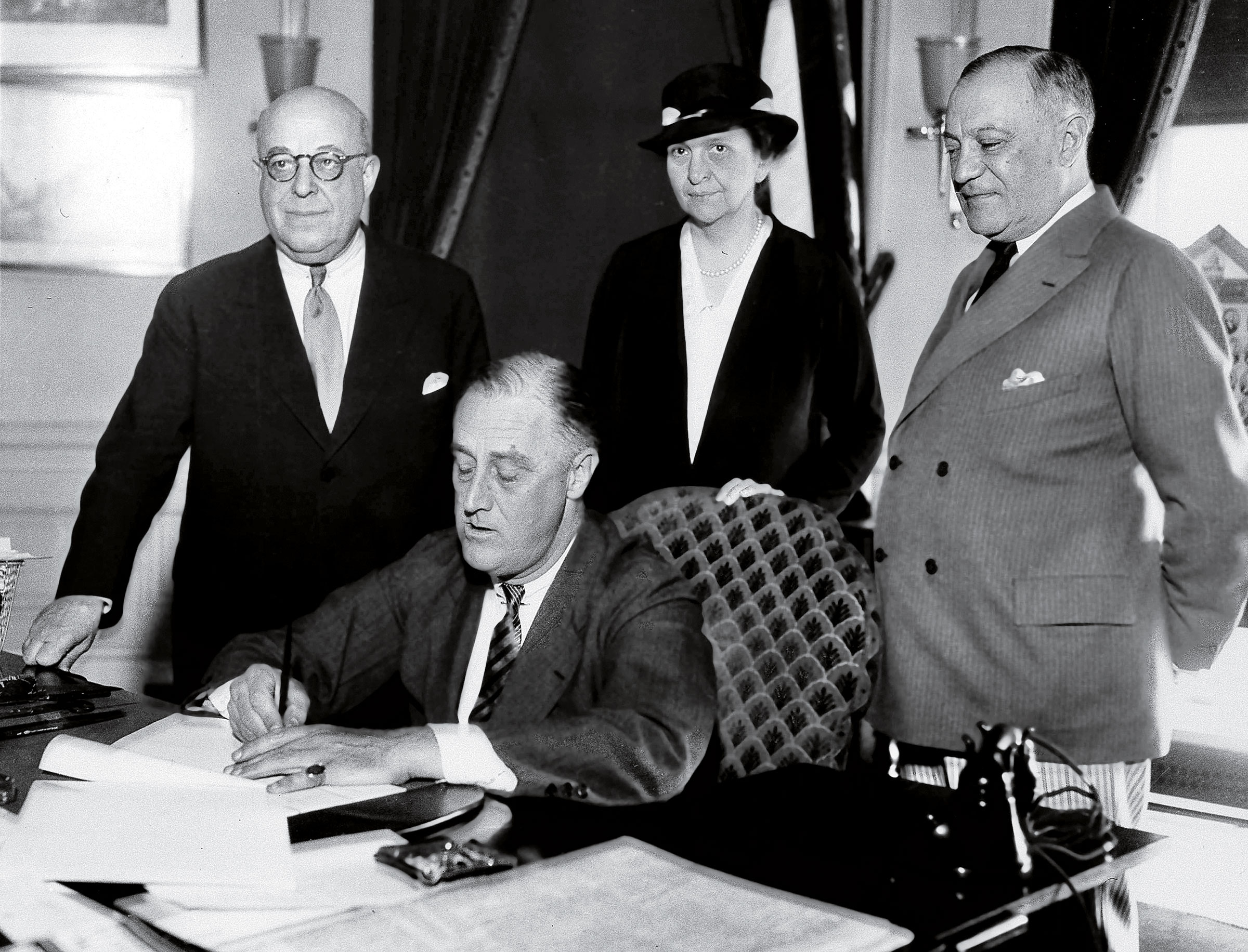 Perkins, behind President Roosevelt as he signs part of the New Deal into law on June 6, 1933. (AP)