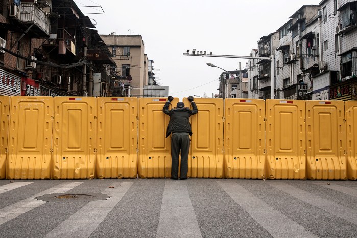 A man talks to another man through a makeshift barricade, built to control entry and exit to a residential compound, in Wuhan, China, on March 8.