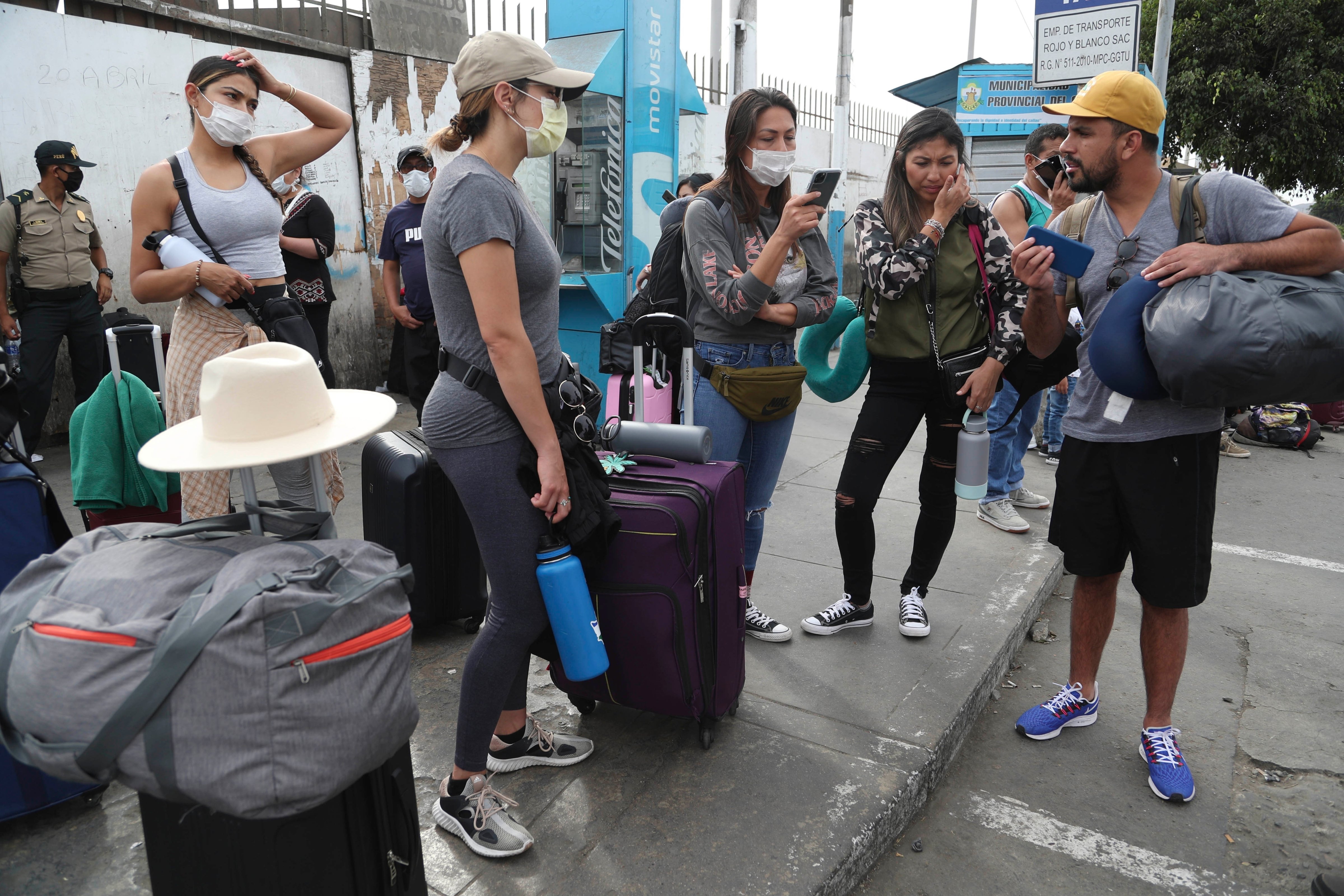 Tourists from the United States wait outside the closed Jorge Chavez International Airport for a member of the U.S. Embassy to escort them to a flight that will fly them back to the U.S., in Callao Peru, Friday, March 20, 2020, on the fifth day of a state of emergency decreed by the government to prevent the spread of the new coronavirus. (AP Photo/Martin Mejia)
