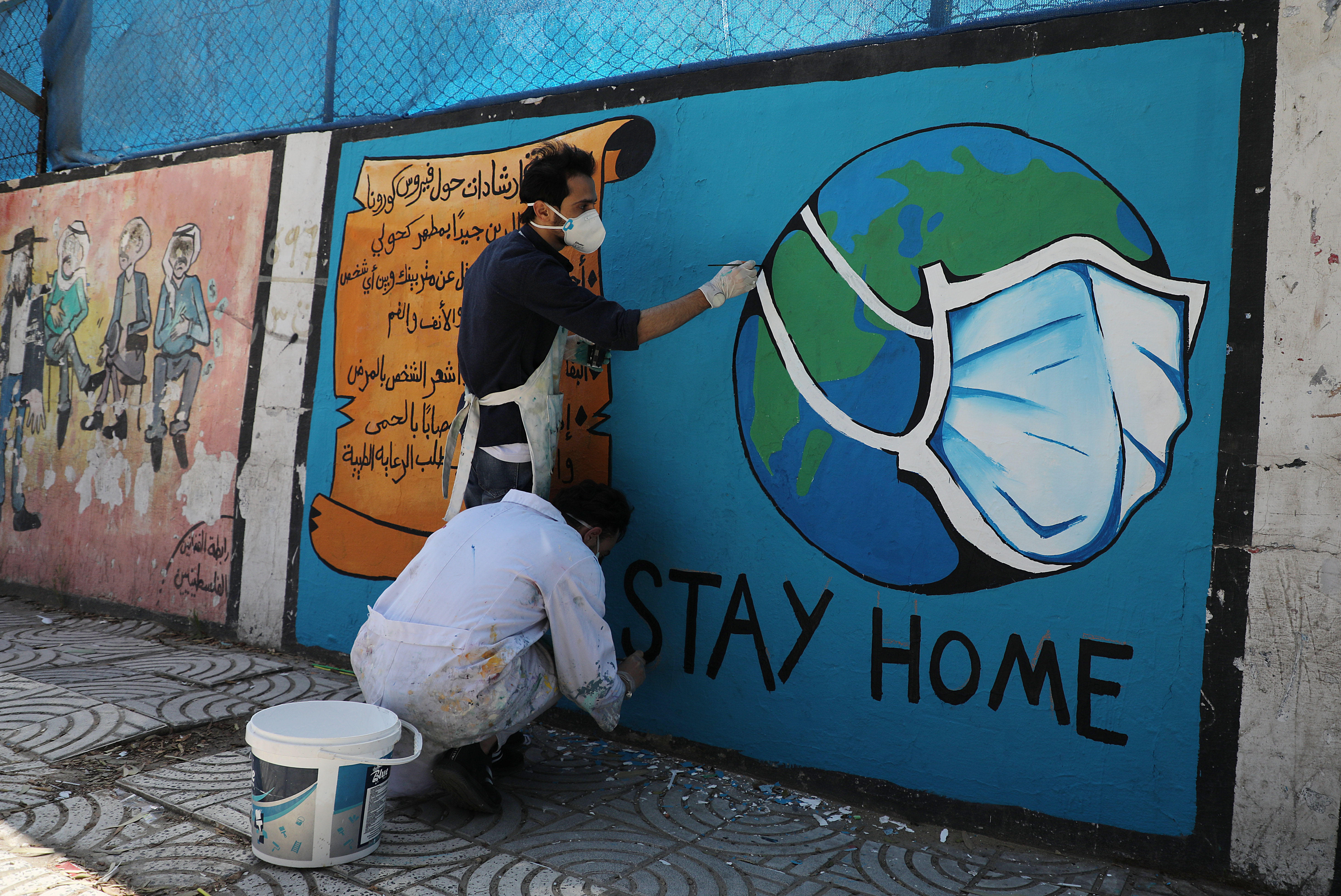 Palestinian artists draw a mural during awareness campaign about the coronavirus COVID-19, in Gaza on April 2,2020.