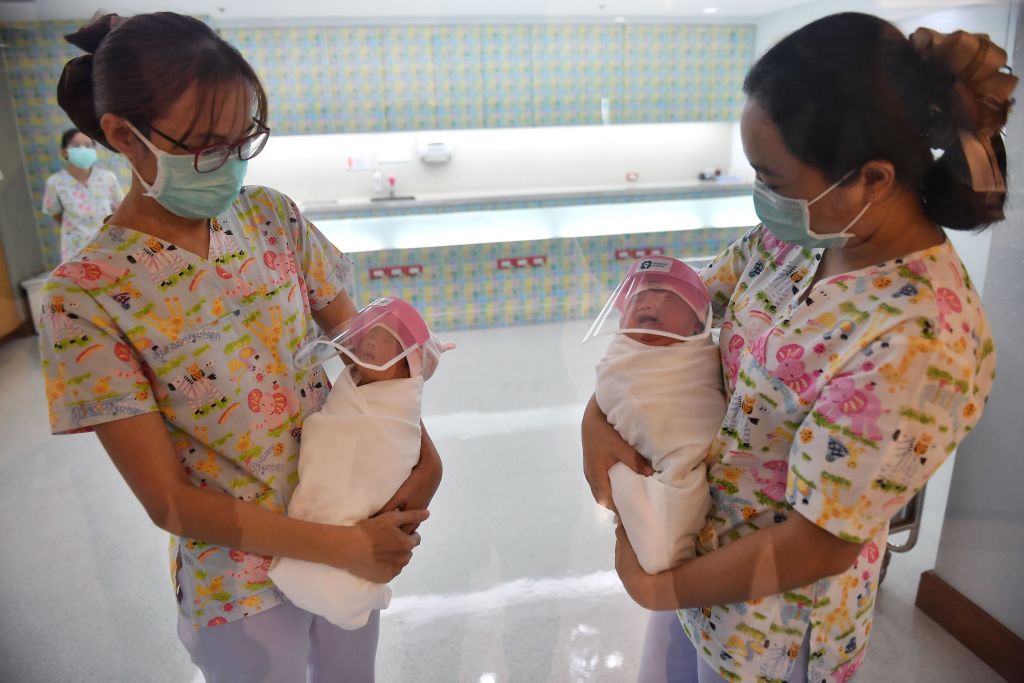 This photo taken through a glass window at a maternity ward shows nurses holding newborn babies wearing face shields, in an effort to halt the spread of the COVID-19 coronavirus, at Praram 9 Hospital in Bangkok on April 9, 2020. (Photo by Lillian Suwanrumpha/AFP—Getty Images)