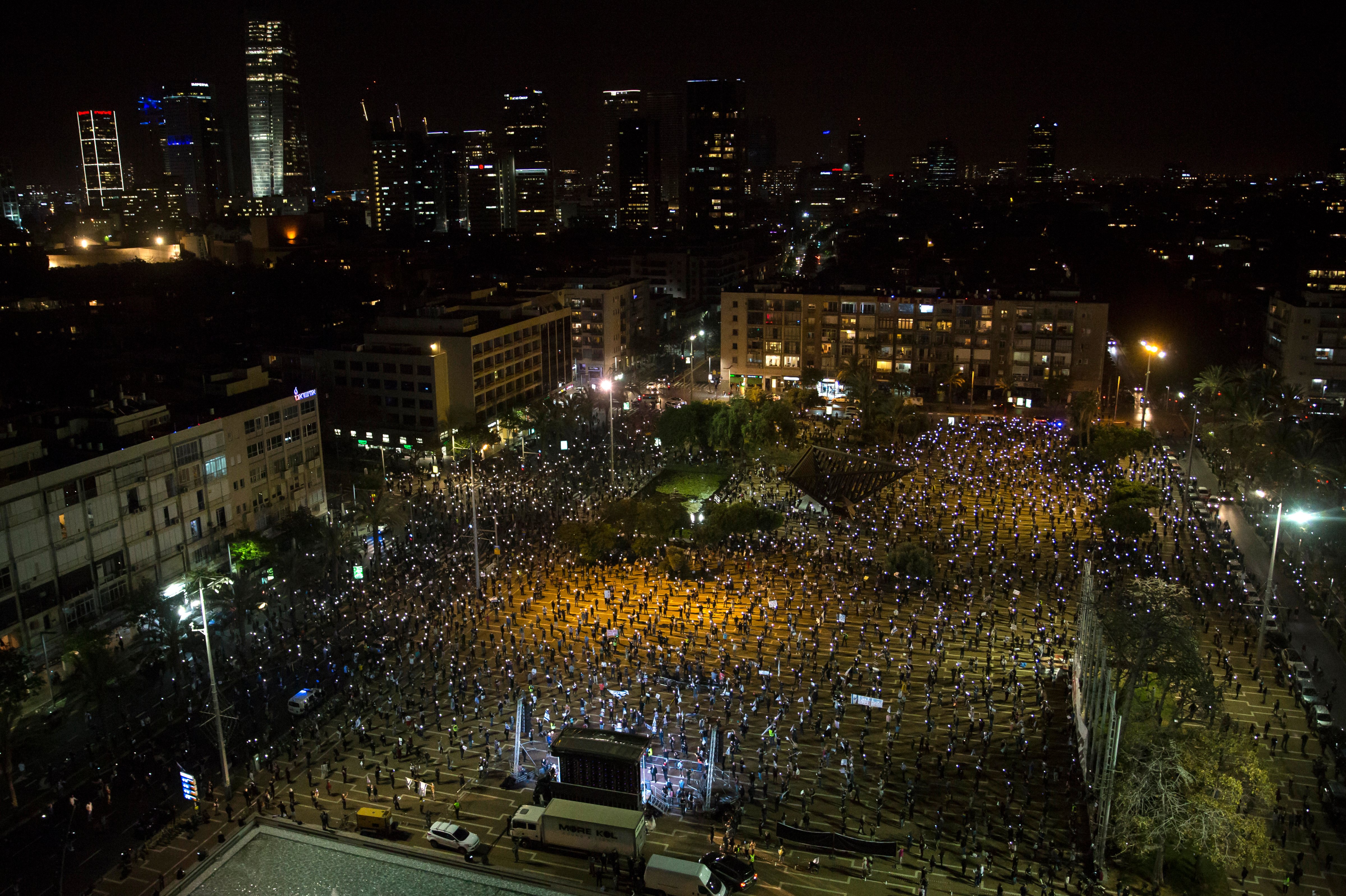 Israelis light flash lights as they protest at a rally in Rabin Square on April 19, 2020 in Tel Aviv, Israel. Thousands of Israelis gather at an Anti-Corruption rally under coronavirus restrictions, decrying proposed unity government talks between Israeli Prime Minister Benjamin Netanyahu, and Blue and White Party leader Benny Gantz. (Photo by /Getty Images) (Amir Levy—Getty Images)