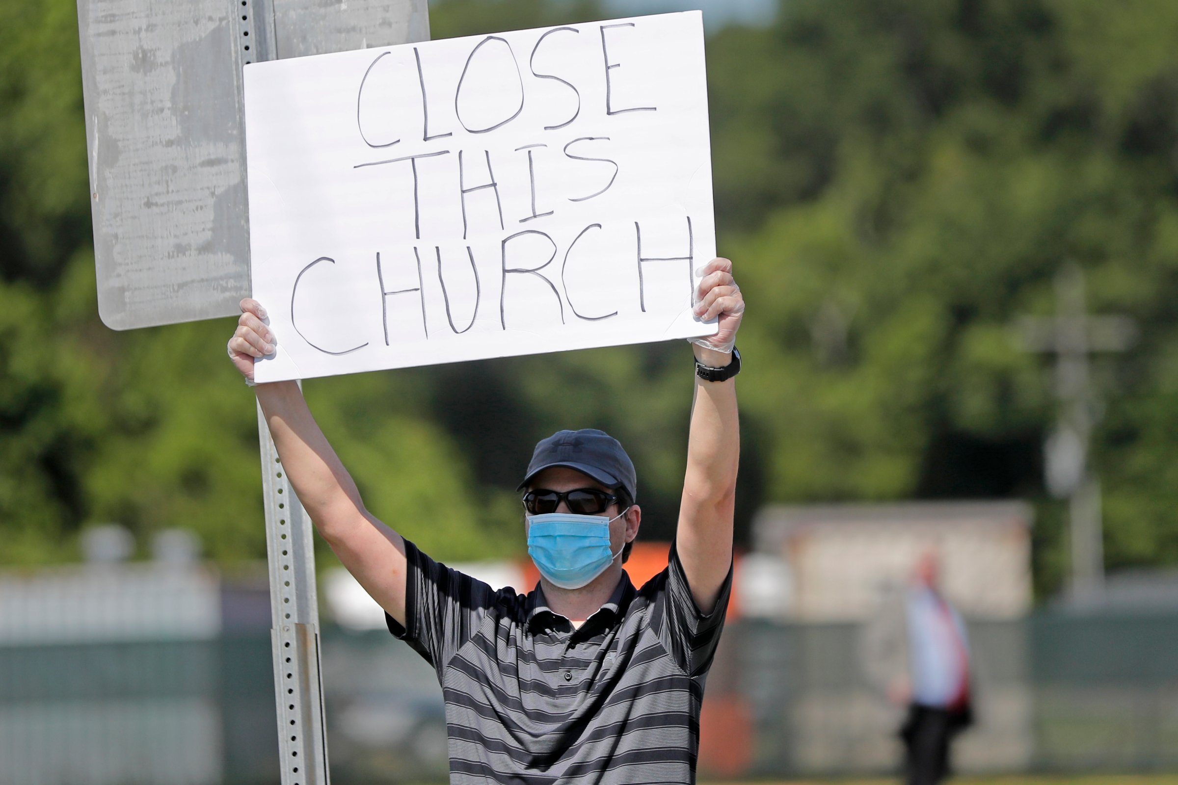 Protestor Trey Bennett holds a sign towards members of the Life Tabernacle Church