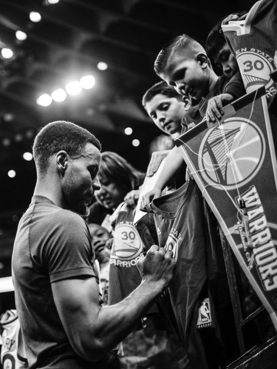 NBA player Steph Curry signs a jersey for a fan