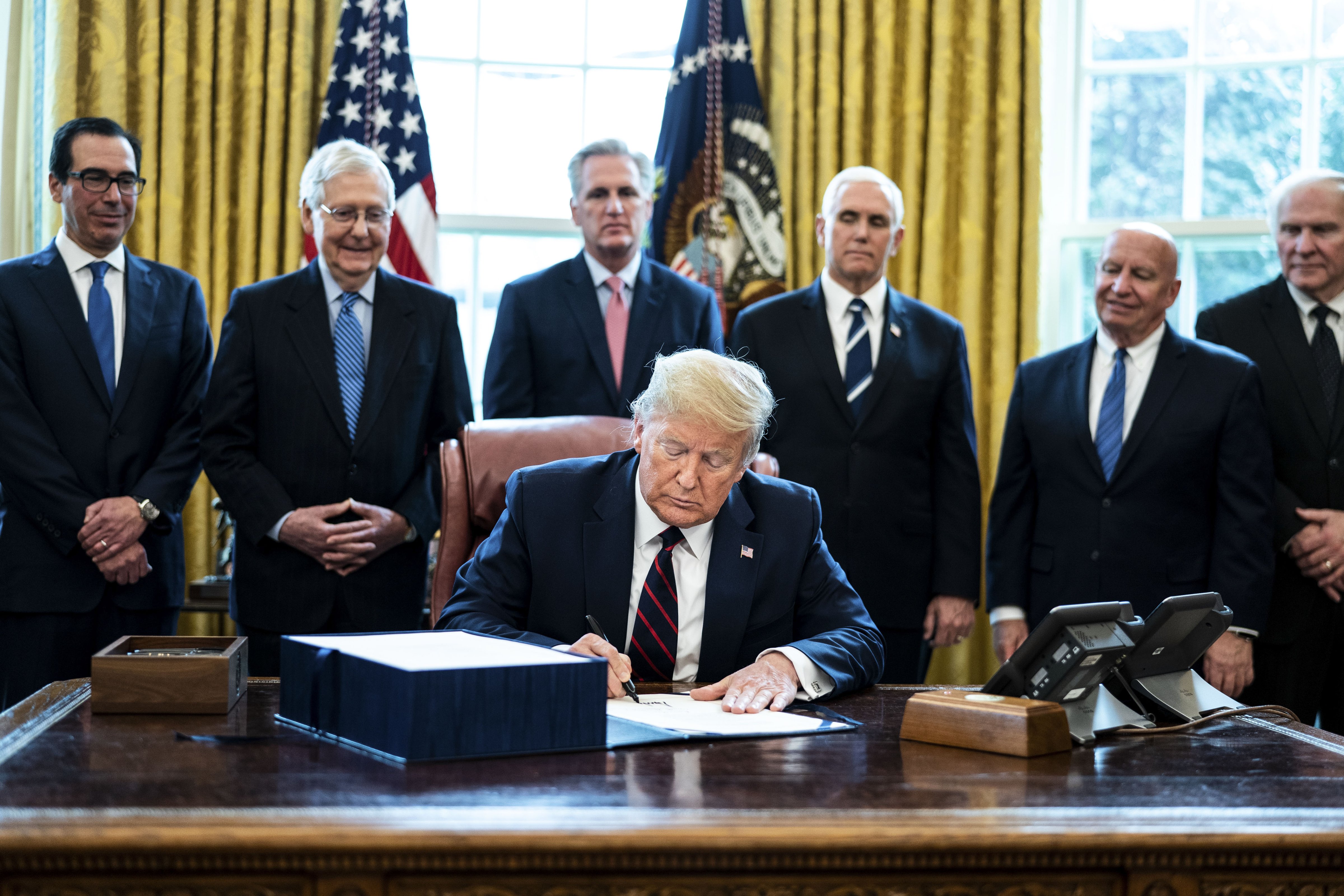 President Donald Trump signs the Coronavirus Aid, Relief, and Economic Security (CARES) Act, in the Oval Office of the White House in Washington, D.C., on Friday, March 27, 2020. (Erin Schaff—The New York Times/Bloomberg/Getty Images)