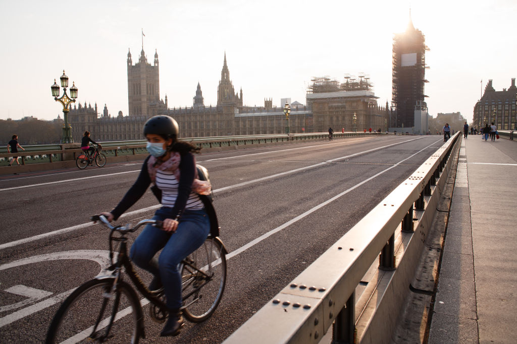 A cyclist wearing a face mask rides across a near-deserted Westminster Bridge in London, England, on April 8, 2020. (David Cliff –NurPhoto/Getty Images)