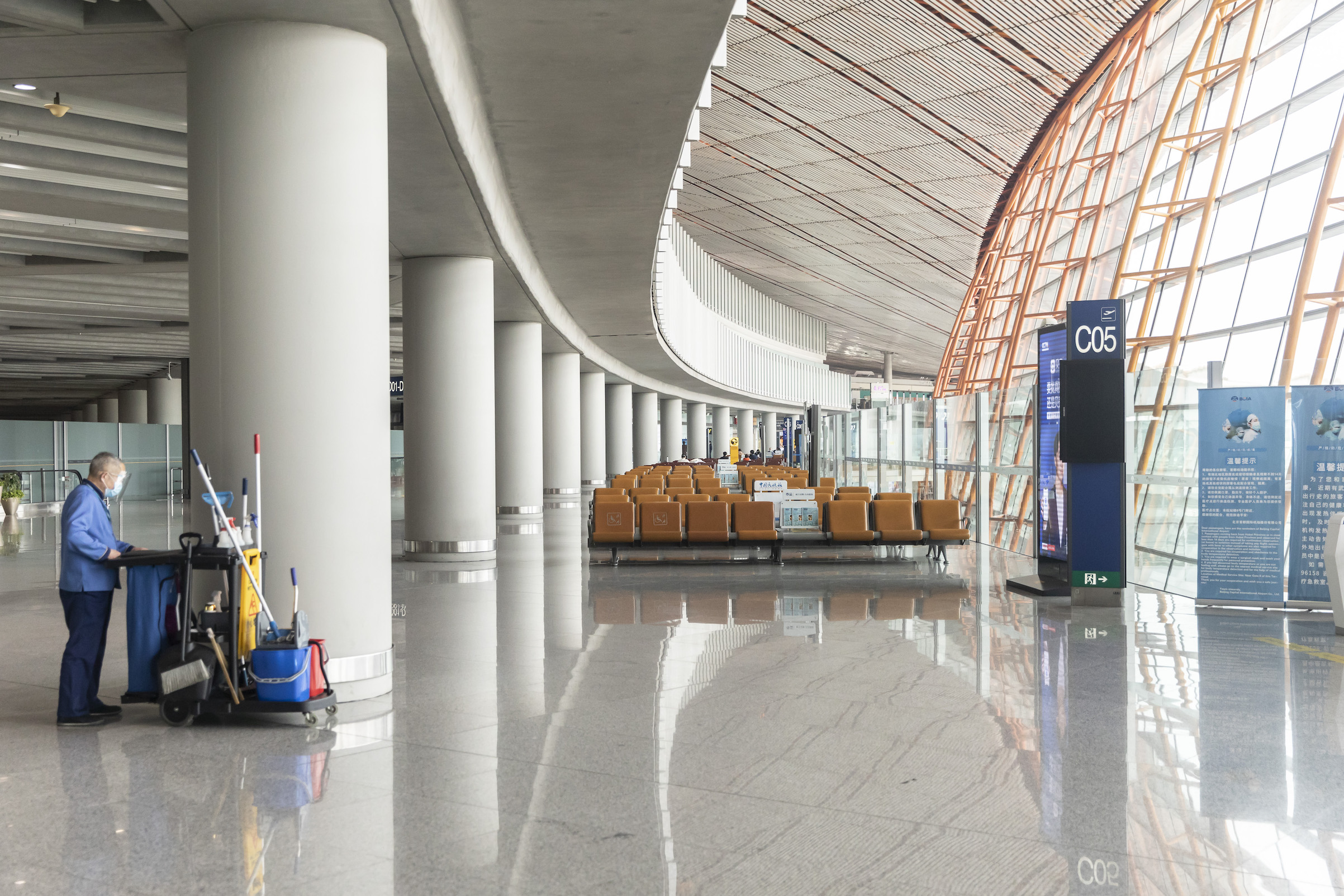 A cleaner wearing a protective mask works in a near-empty departure hall at Terminal Three of the Capital International Airport in Beijing, on March 18, 2020. (Bloomberg via Getty Images)