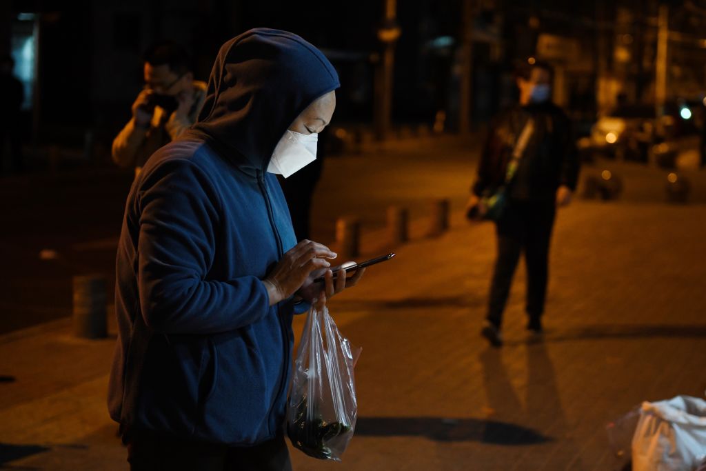 A woman wearing a facemask as a preventive measure against the COVID-19 novel coronavirus prepares to pay 'touchless' with her mobile phone for vegetables at a market in Beijing on March 23, 2020. (Emanuele Cremaschi — Getty Images)