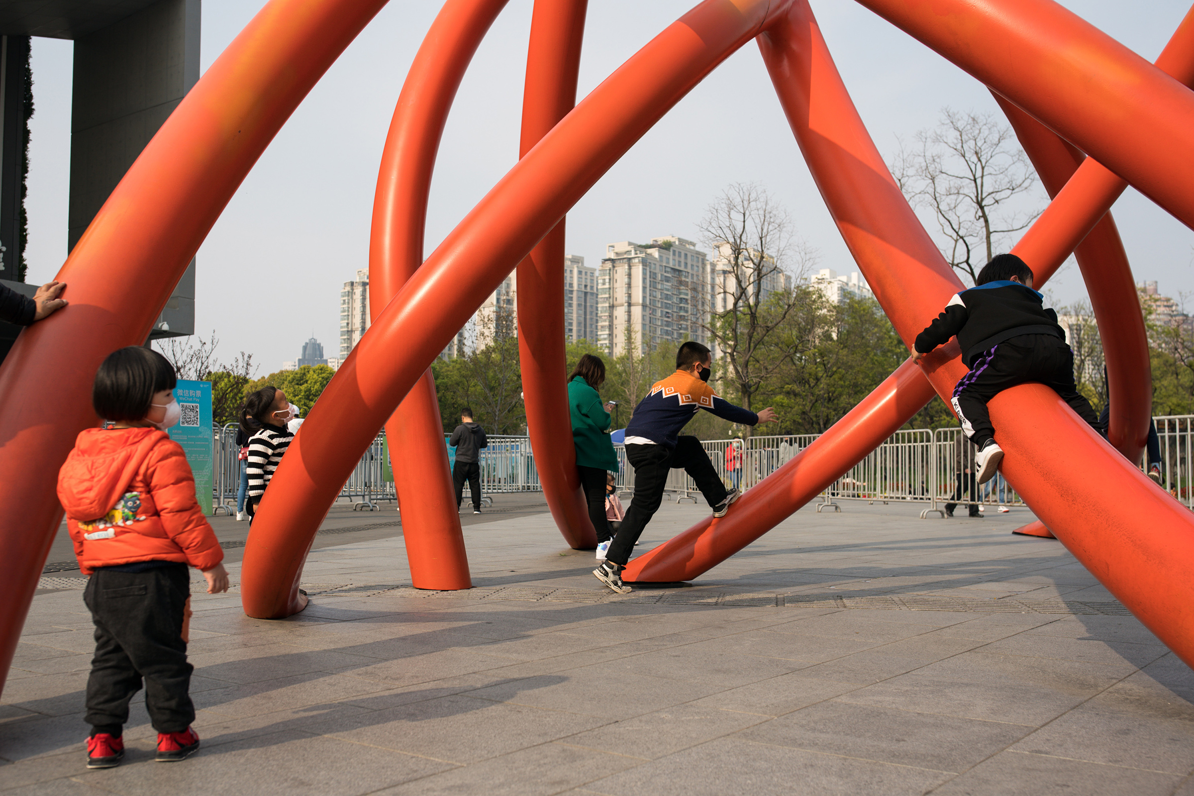 Children wear protective masks while playing under a sculpture in a city park on April 01, in Shanghai, China