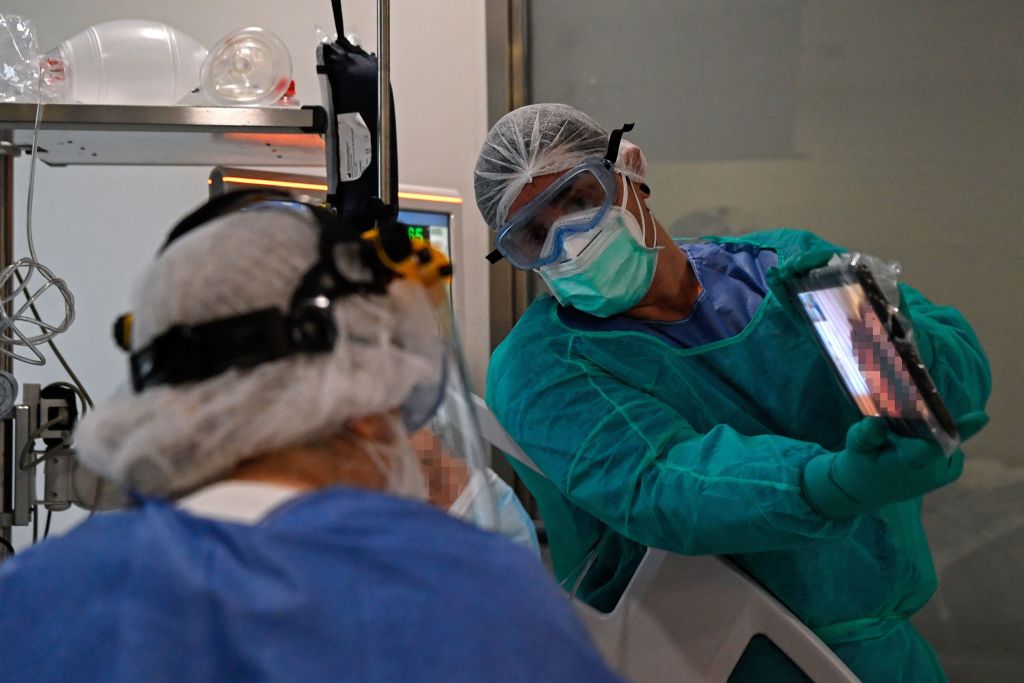 Healthcare workers hold a tablet in front of a COVID-19 coronavirus patient during a video call with relatives at the Intensive Unit Care (ICU) of the Ramon y Cajal Hospital in Madrid on April 14, 2020. (Oscar Del Pozo — AFP via Getty Images)
