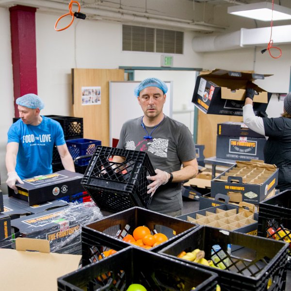 Michael McCormick and Daniel Cohen, of Project Open Hand, and Cindy Neill, operations manager for The Fruit Guys,
                                sort through a palette of donated fruit boxes in the volunteer space at Project Open Hand in San Francisco, Calif. on March 25, 2020.