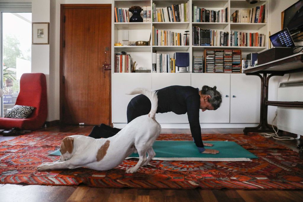 This picture taken on March 23, 2020 shows a woman taking part in an online pilates class at home, as her dog Elvis stretches next to her, in Nicosia, as restrictions on movement and social distancing were imposed across Cyprus to contain the spread of the COVID-19 novel coronavirus. (Christina Assi — AFP/Getty Images)