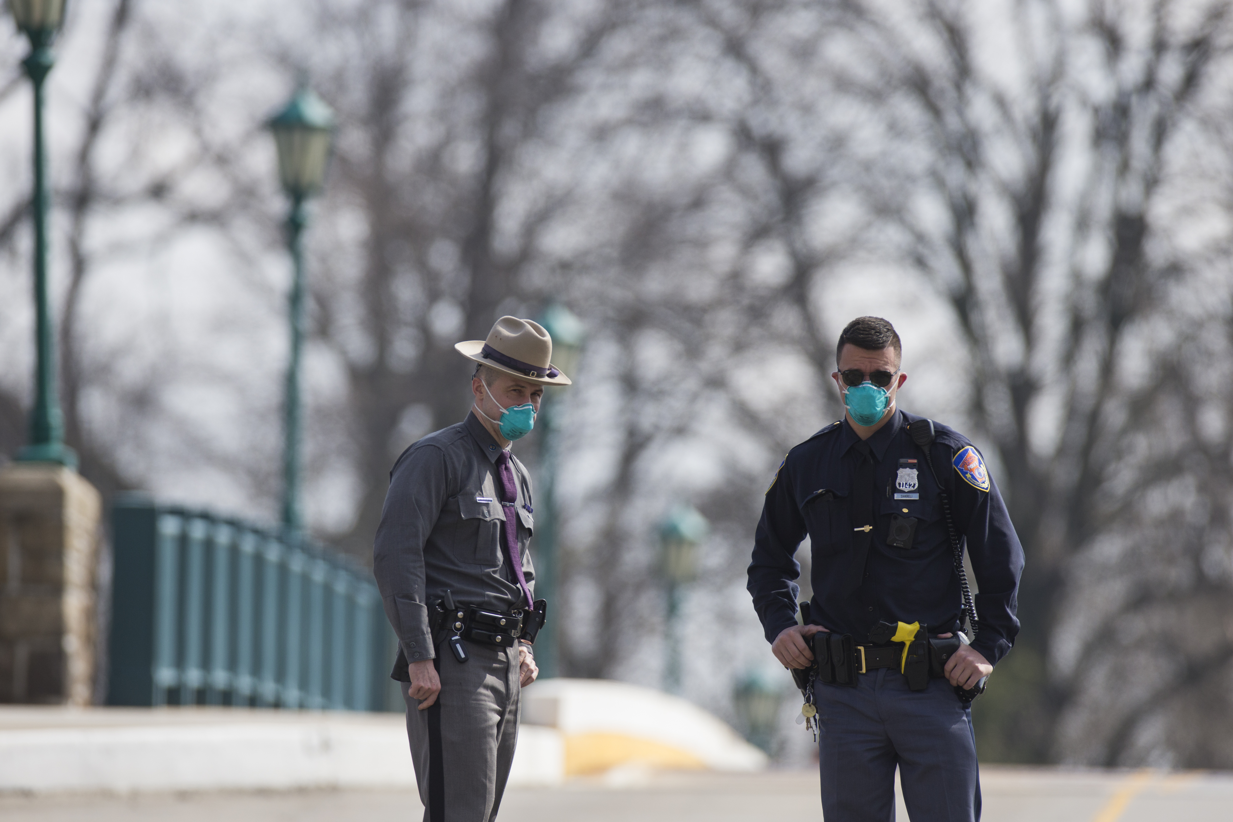 Police officers wear protective masks while maintaining a road block on the bridge leading to a  drive-through testing facility at Glen Island Park in New Rochelle, New York, on March 13, 2020. (Angus Mordant—Bloomberg/Getty Images)