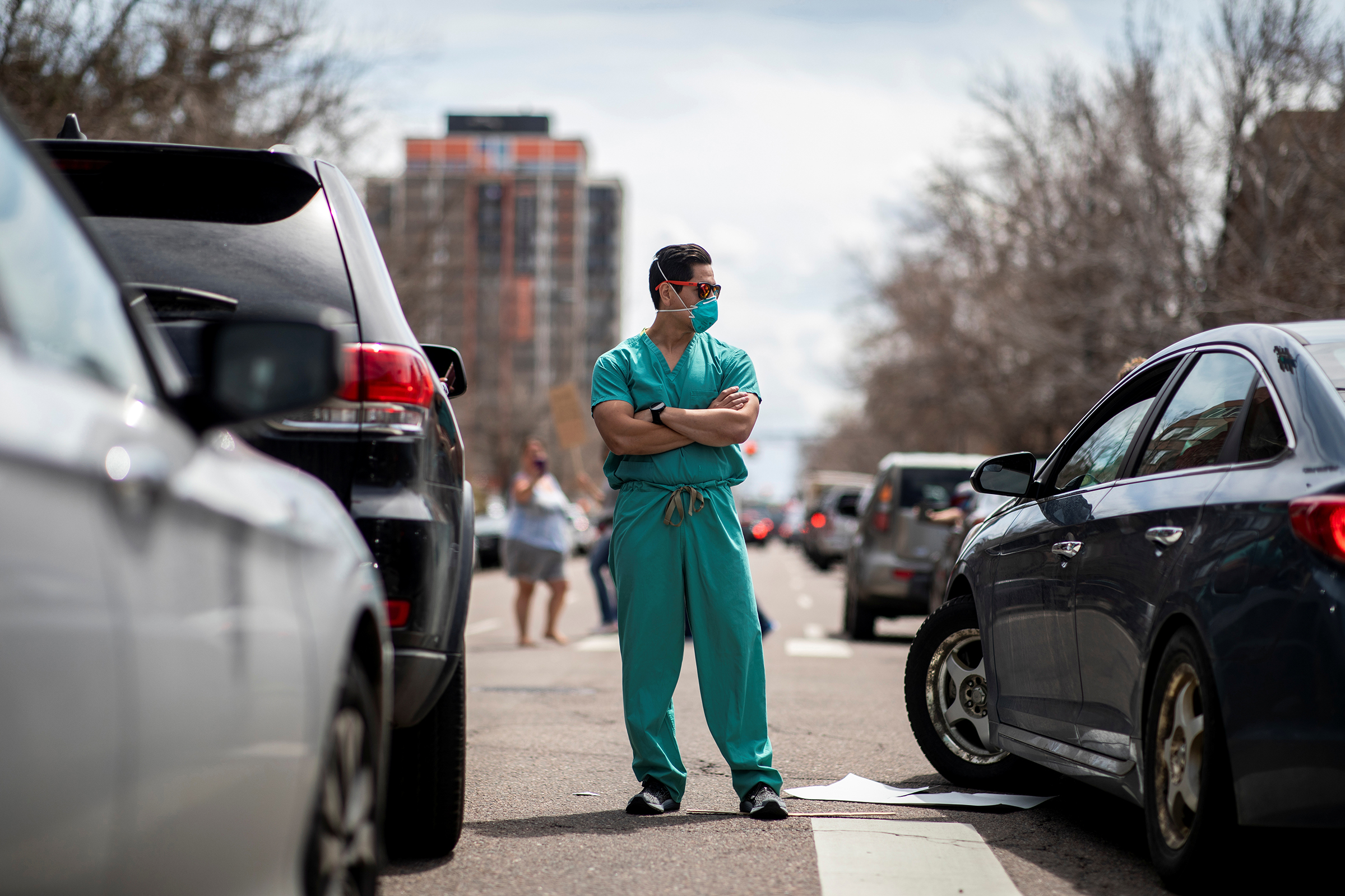 Health care workers stand in the street as a counter-protest to those demanding the stay-at-home order be lifted in Denver