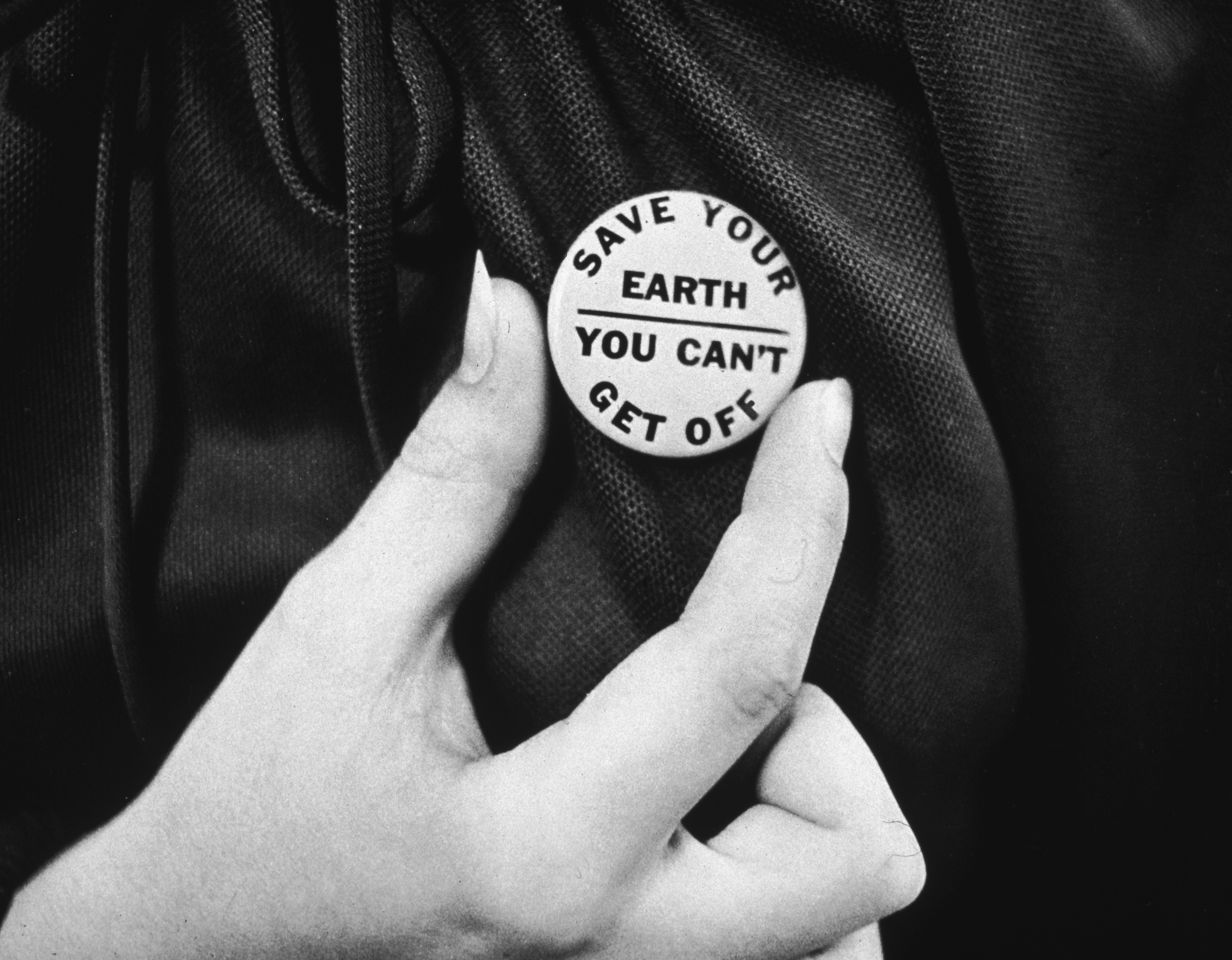 circa 1970:  A close-up of a hand holding up an Earth Day button. (Getty Images)