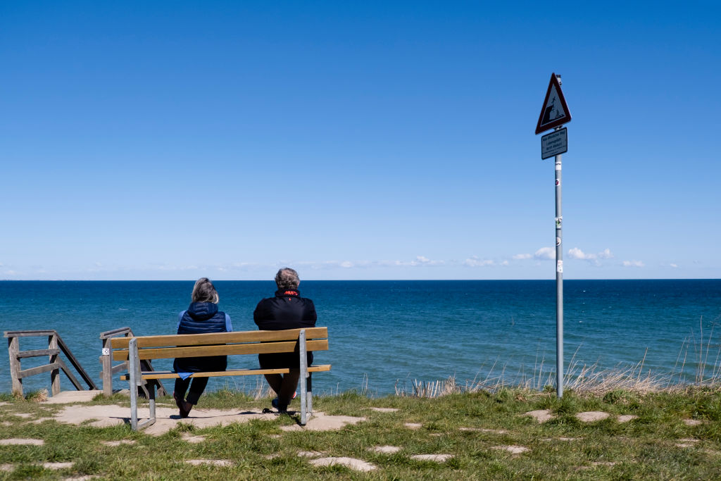 Two people sit on a bench at the Stohler Steep Coast and look out over the Baltic Sea. (Frank Molter–picture alliance/Getty Images)