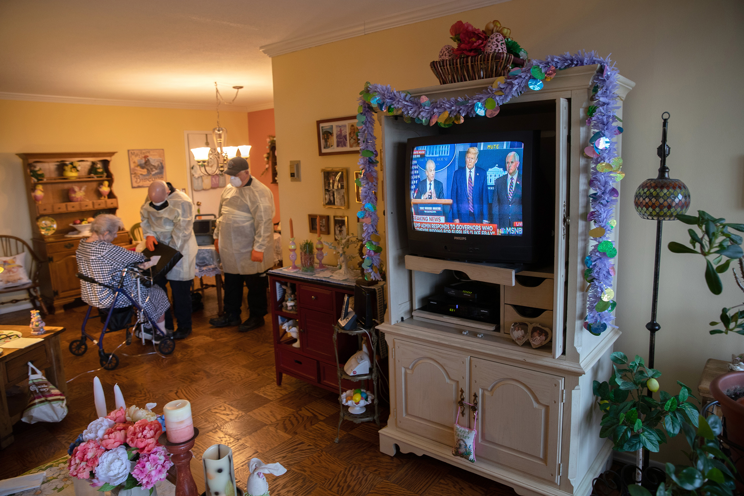 EMS medics wearing personal protective equipment check a woman in her apartment for COVID-19 symptoms during a televised Presidential press conference on April 02 in Stamford, Connecticut. (John Moore—Getty Images)