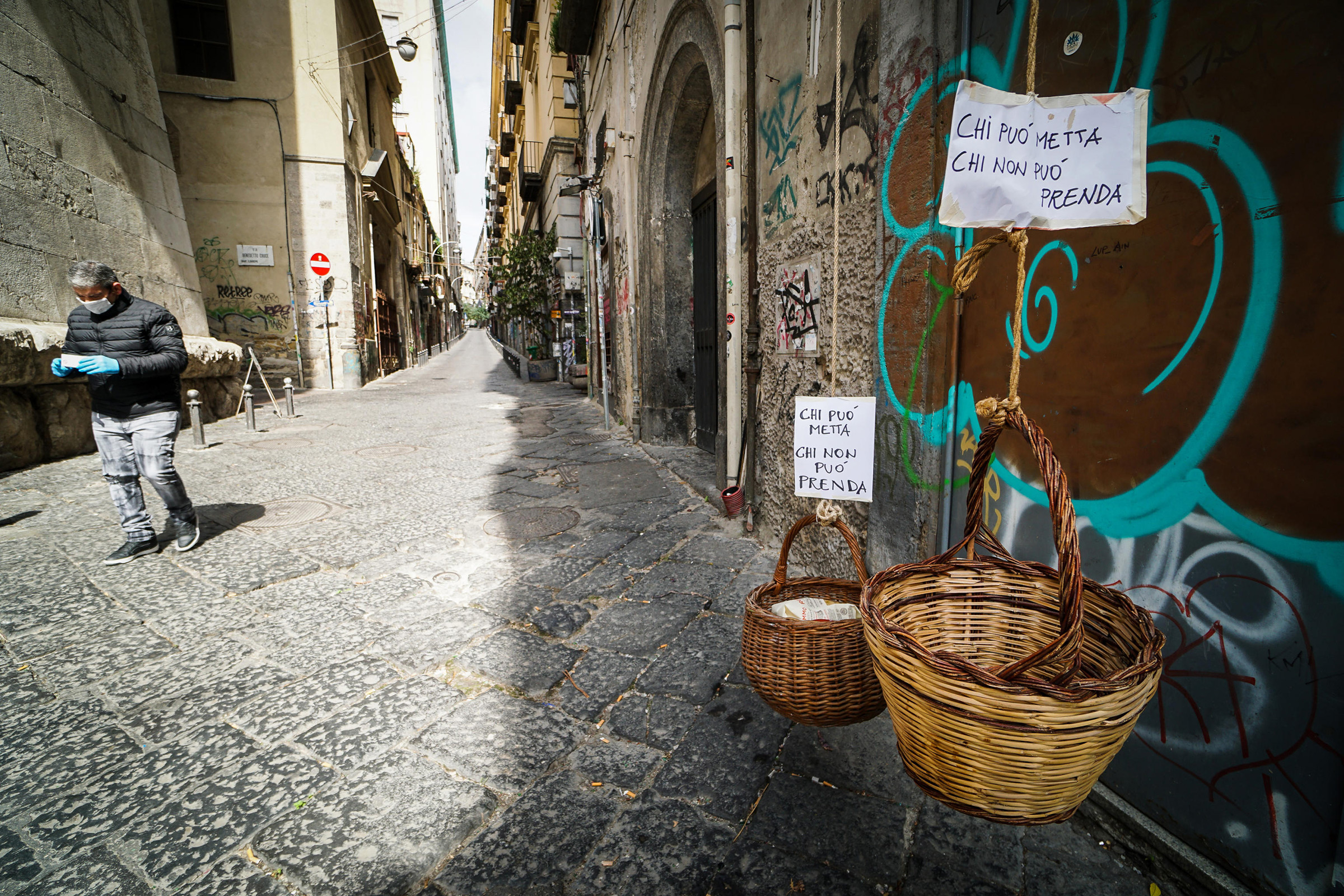 Solidarity baskets with notes reading 'Who can may put, who cannot may take' in one of the deserted streets in the historic center of Naples, southern Italy, on March 30, 2020. (Cesare Abbate—EPA-EFE/Shutterstock)