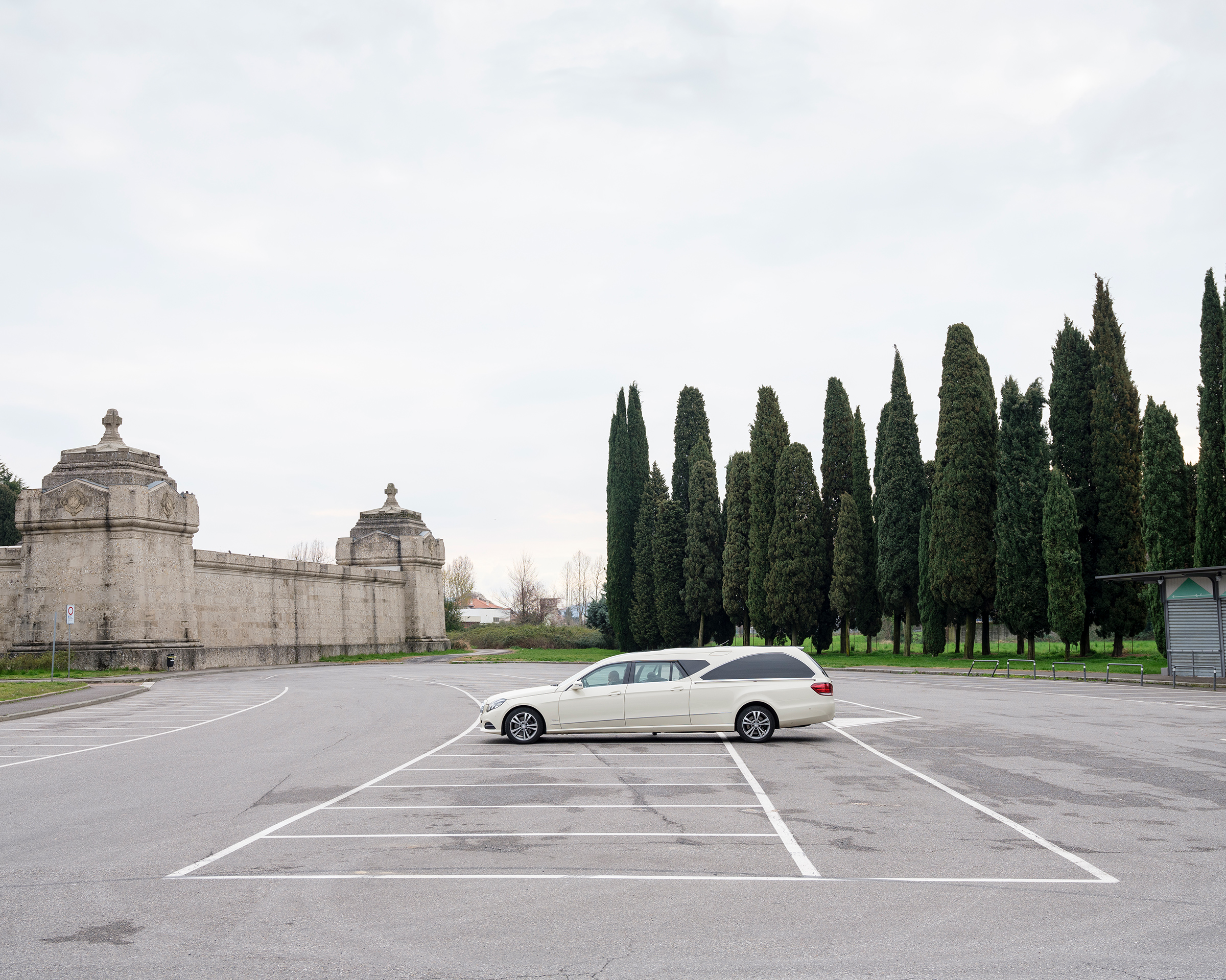A hearse driver outside a cemetery in Bergamo awaits information about the next destination.