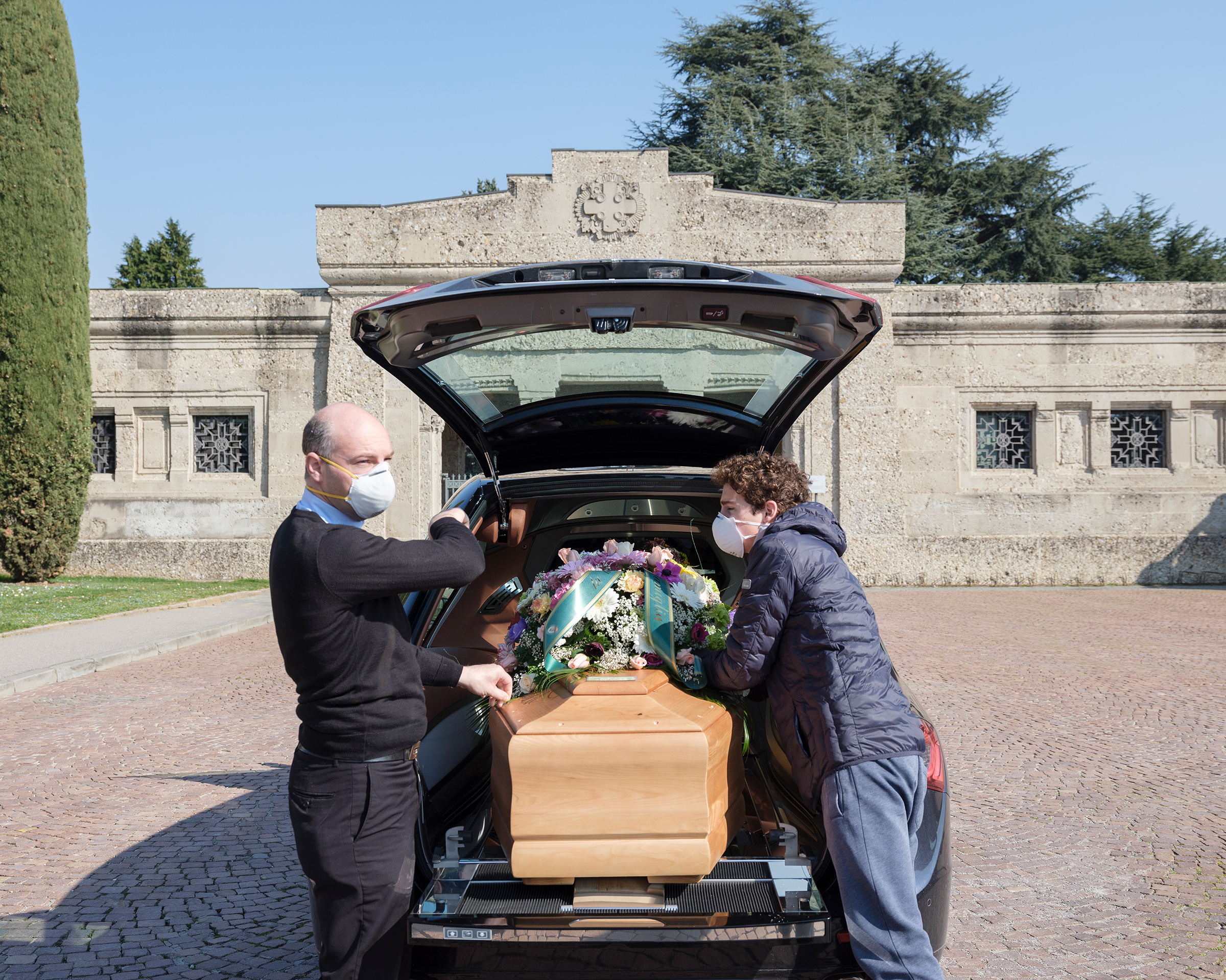 An undertaker and a young family member accompany a coffin at a cemetery in Bergamo. While funerals are prohibited, few close family members can accompany a coffin during the burial.
