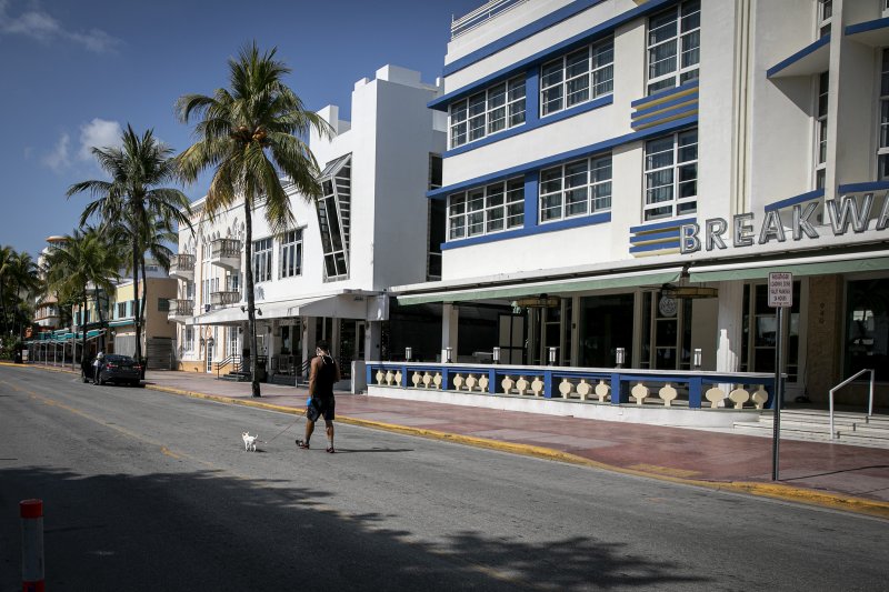 A pedestrian walks a dog in the middle of an empty street in Miami, Florida, on April 8, 2020. Marco Bello—Bloomberg via Getty Images