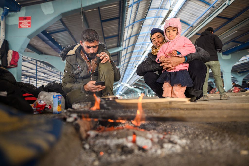 Syrian refugees sit around a campfire in an empty market hall in the Turkish border town of Edirne near the Pazarkule-Kastanies border crossing on March, 5 2020. (Mohssen Assanimoghaddam—DPA/Getty Images)