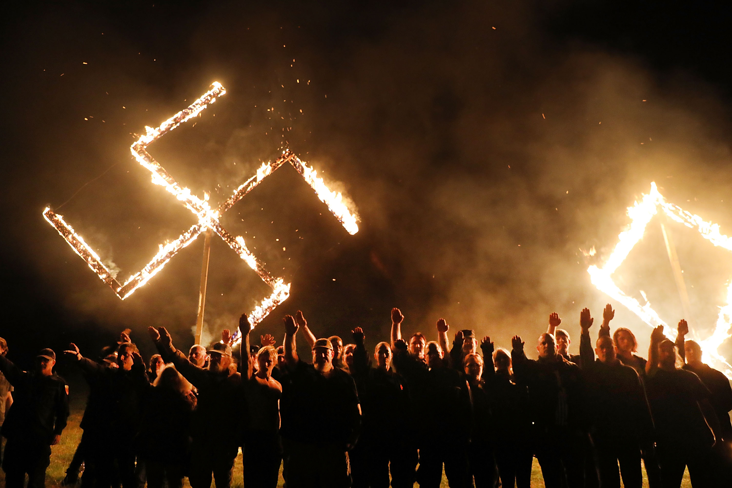 Members  of the National Socialist Movement, one of the largest neo-Nazi groups in the US, hold a swastika burning on April 21, 2018 in Draketown, Georgia. (Spencer Platt—Getty Images)