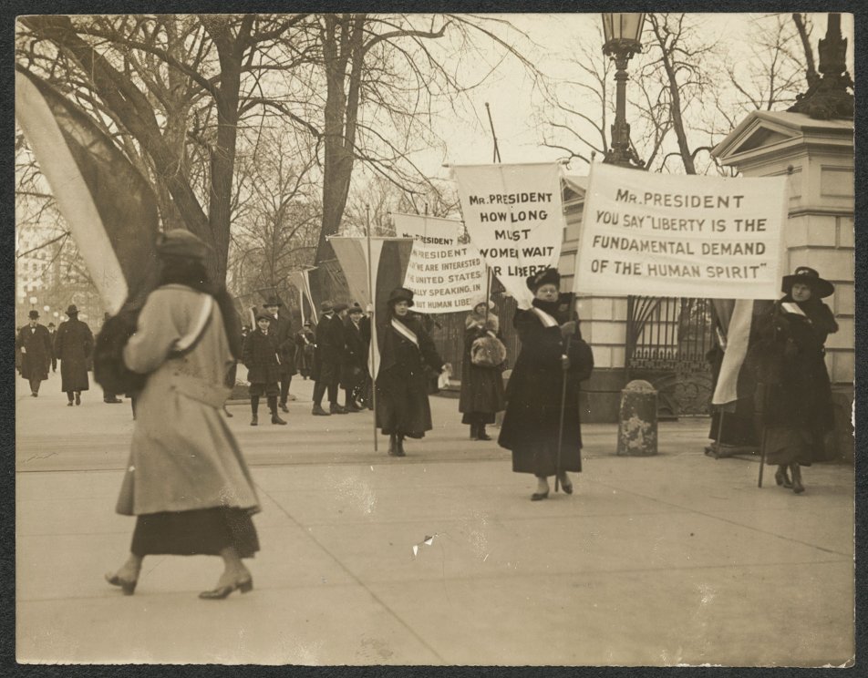 Suffragists picket with banners on the sidewalk in front of White House gates on Jan. 26, 1917.