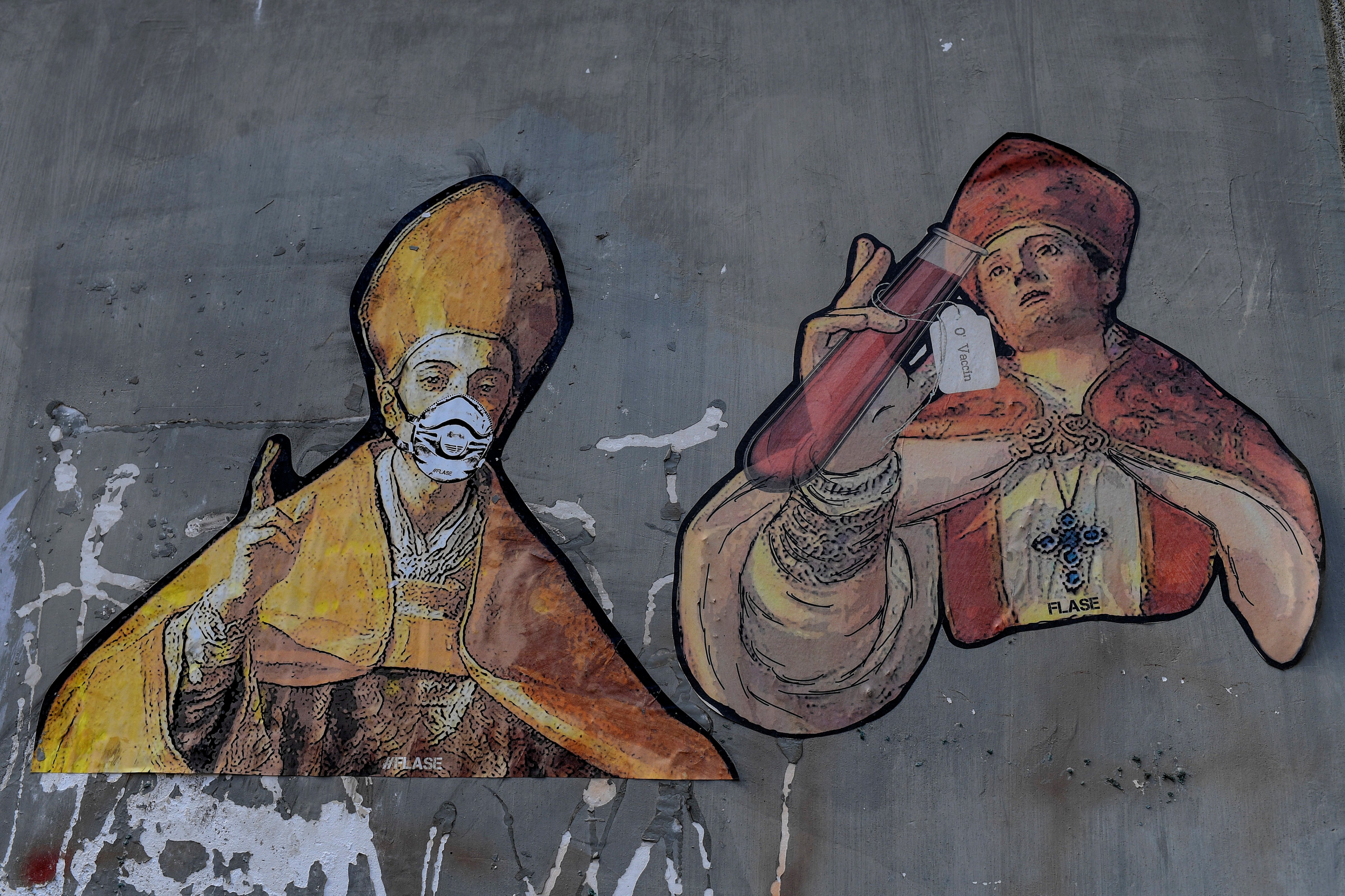 A mural depicting two figures of Saint Gennaro, patron of Naples, with a protective mask and an ampule with the label "The vaccine" written in Napolitan on a wall in the city's downtown, on May 11, 2020. (Salvatore Laporta—KONTROLAB/LightRocket via Getty Images)