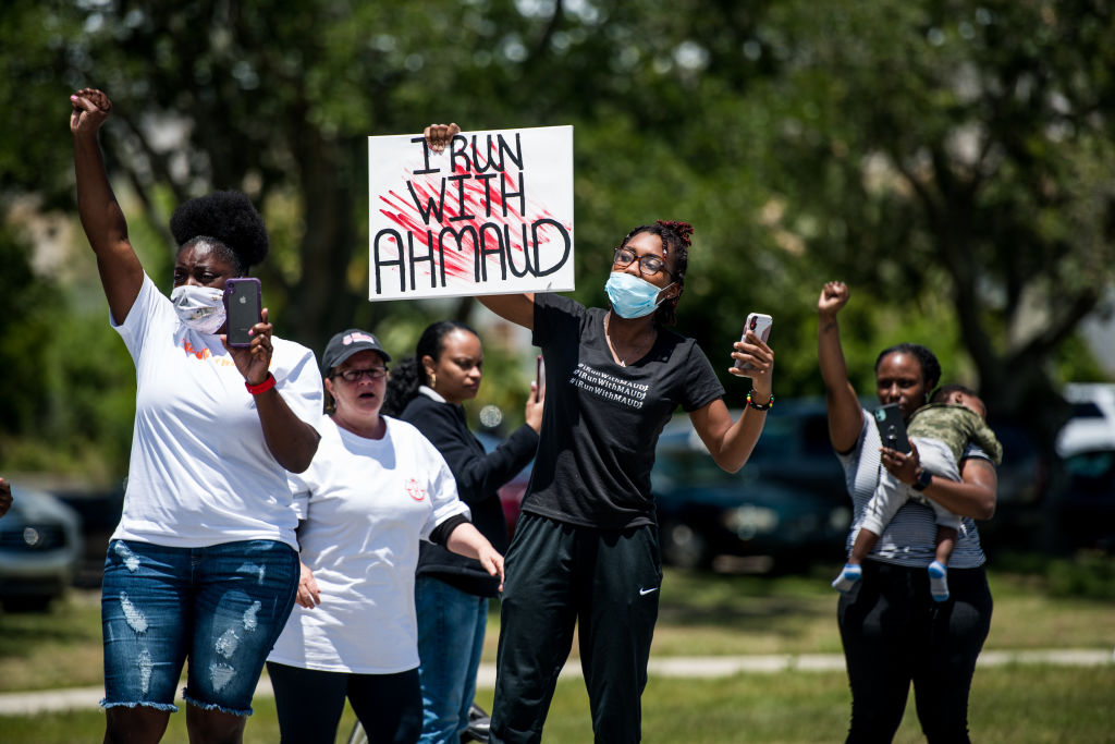Demonstrators raise their fists at a parade of passing motorcyclists riding in honor of Ahmaud Arbery at Sidney Lanier Park on May 9 in Brunswick, Georgia. Arbery was shot and killed while jogging in the nearby Satilla Shores neighborhood on Feb. 23. (Sean Rayford / Stringer)