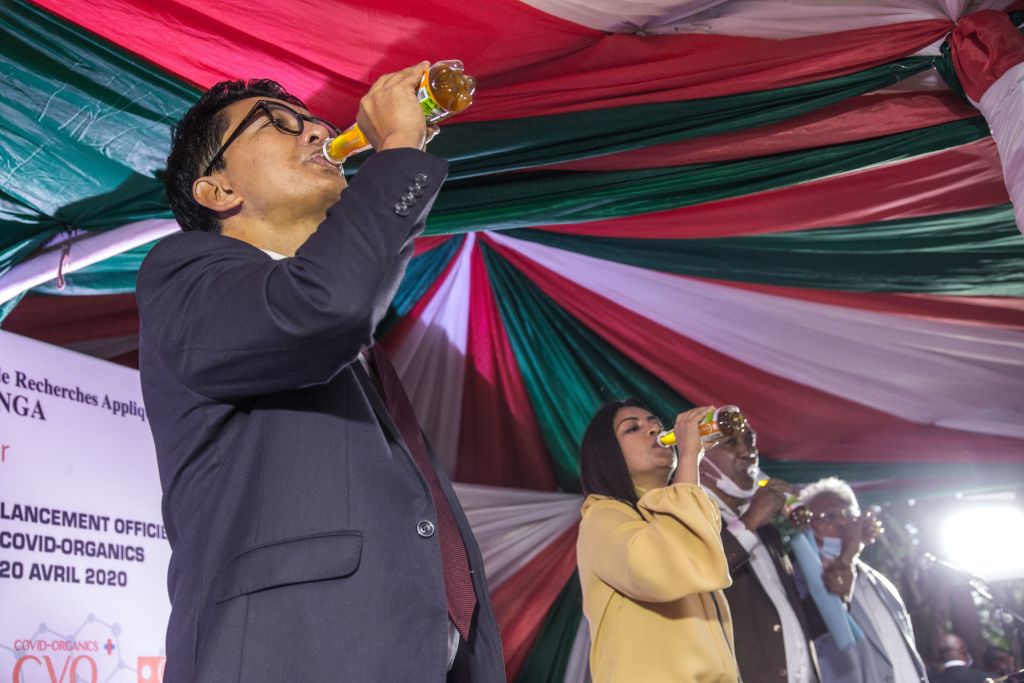 Madagascar's President Andry Rajoelina drinks a sample of the 