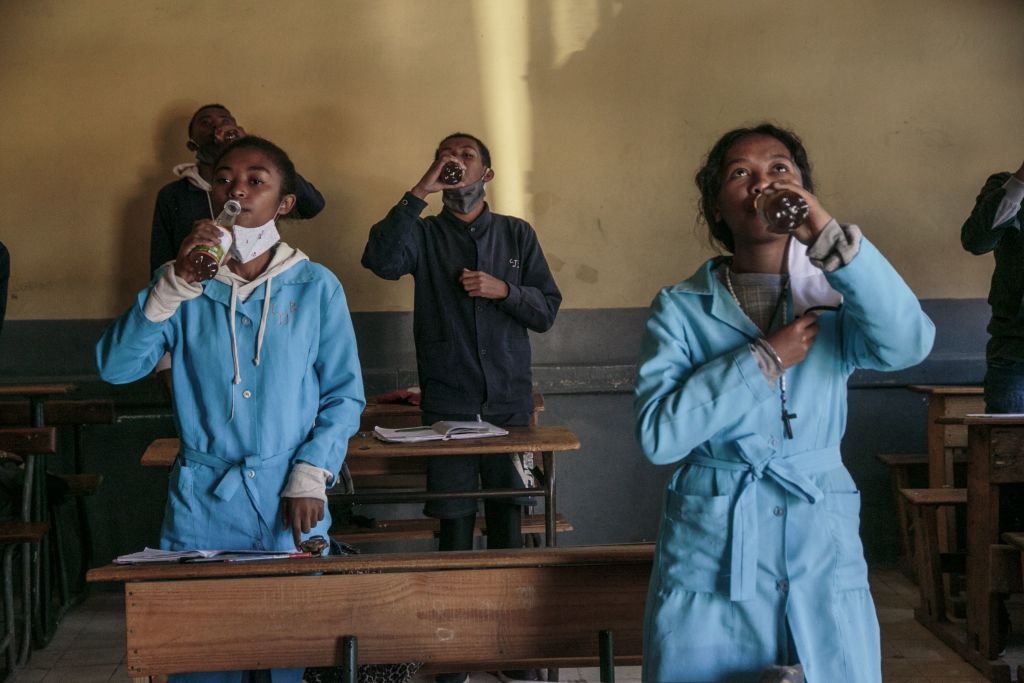 Students at the J.J. Rabearivelo High School in Antananarivo, Madagascar drink from bottles of Covid Organics, a herbal tea, touted by  President Andry Rajoelina as a powerful remedy against the COVID-19 coronavirus,  on April 23 2020 (RIJASOLO—AFP via Getty Images)