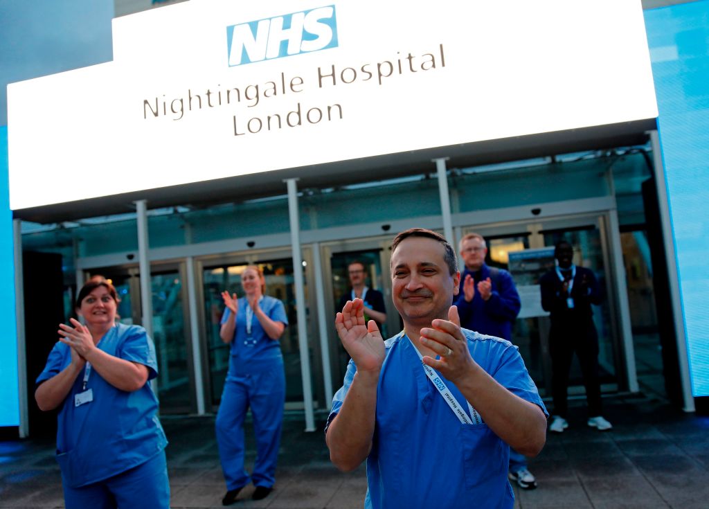 Medical staff and workers take part in a national "clap for carers" to show thanks for the work of Britain's NHS (National Health Service) workers and other frontline medical staff around the country as they battle with the novel coronavirus pandemic, outside of the ExCeL London exhibition centre, which has been transformed into the "NHS Nightingale" field hospital in London on April 30, 2020. (Tolga Akmen—AFP via Getty Images)