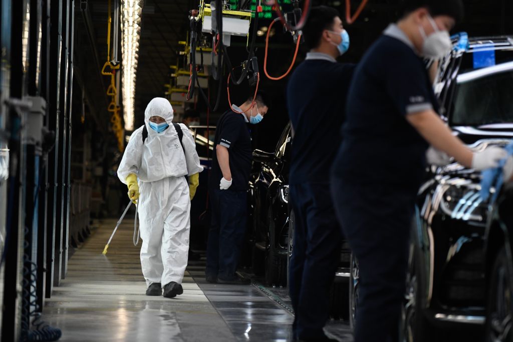 A cleaner wearing protective gear sprays disinfectant along a production line at a Mercedes Benz automotive plant during a media tour organised by the government in Beijing on May 13, 2020, as the country's industrial sector starts again following shutdowns during the COVID-19 coronavirus outbreak. (Wang Zhao/AFP via Getty Images)