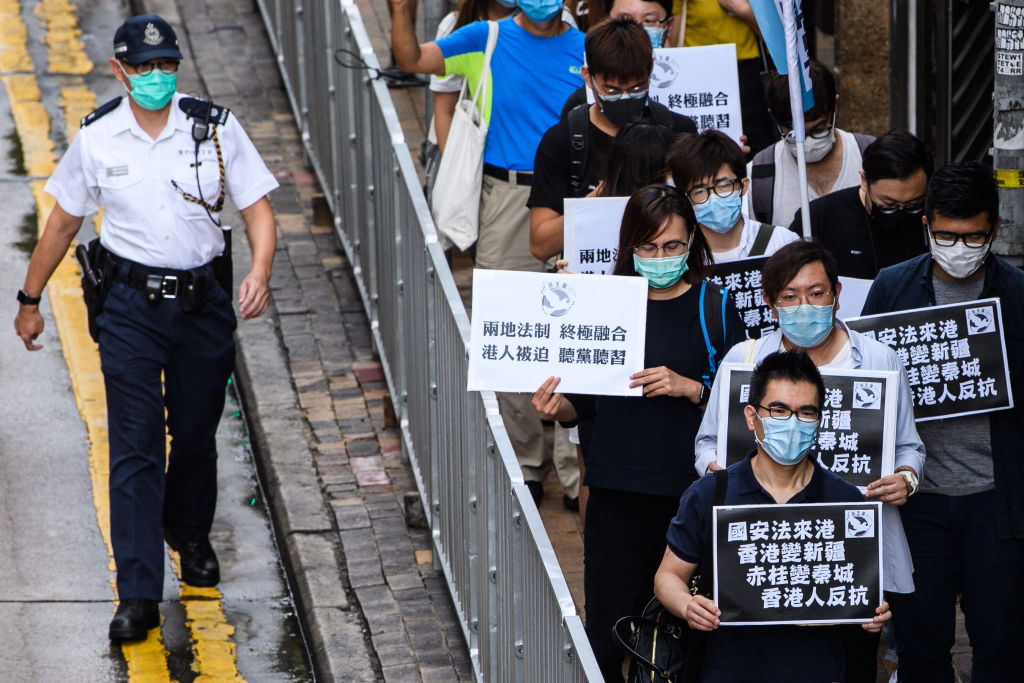 Pro-democracy protesters hold black placards that translate as "National Security Law comes to Hong Kong, Hong Kong becomes Xinjiang, Stanley Prison becomes Qincheng Prison, Hong Kongers Revolt", as they march towards the Chinese Liaison Office in Hong Kong on May 22, 2020. (Anthony Wallace/AFP via Getty Images)