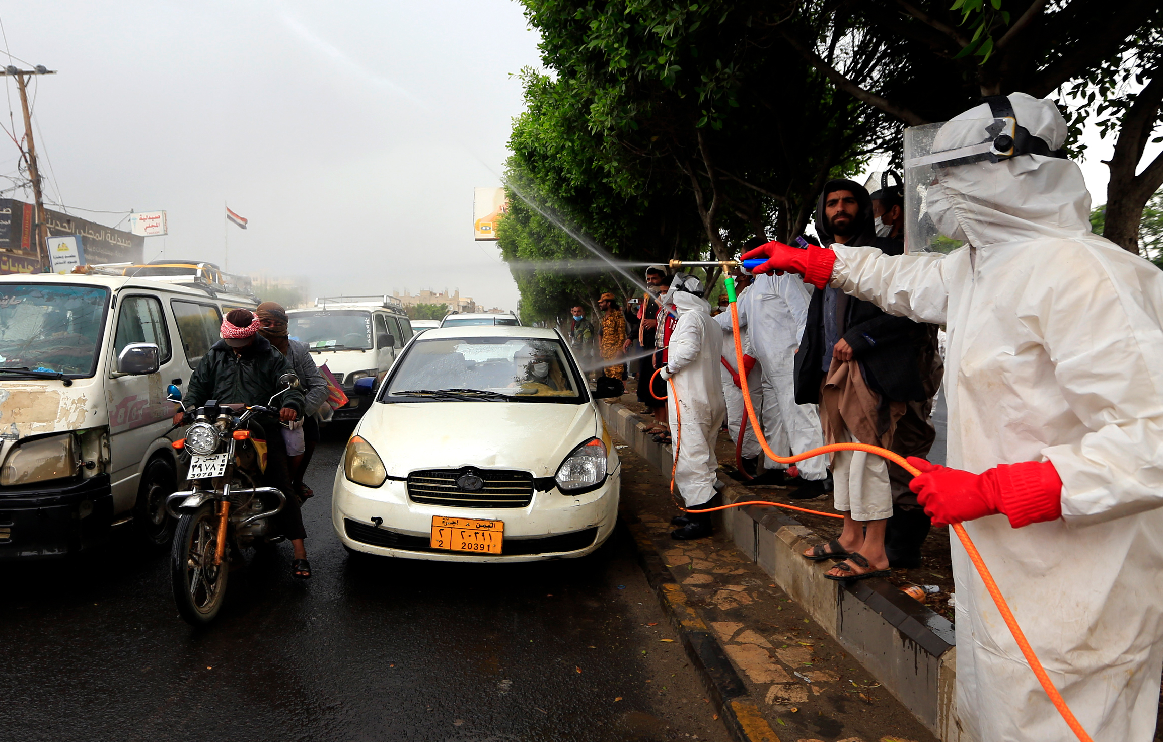 Yemeni workers wearing protective outfits spray disinfectant on passing cars and motorcycles in the capital Sanaa, during the ongoing novel coronavirus pandemic crisis, on May 21, 2020. (Mohammed Huwais—AFP/Getty Images)
