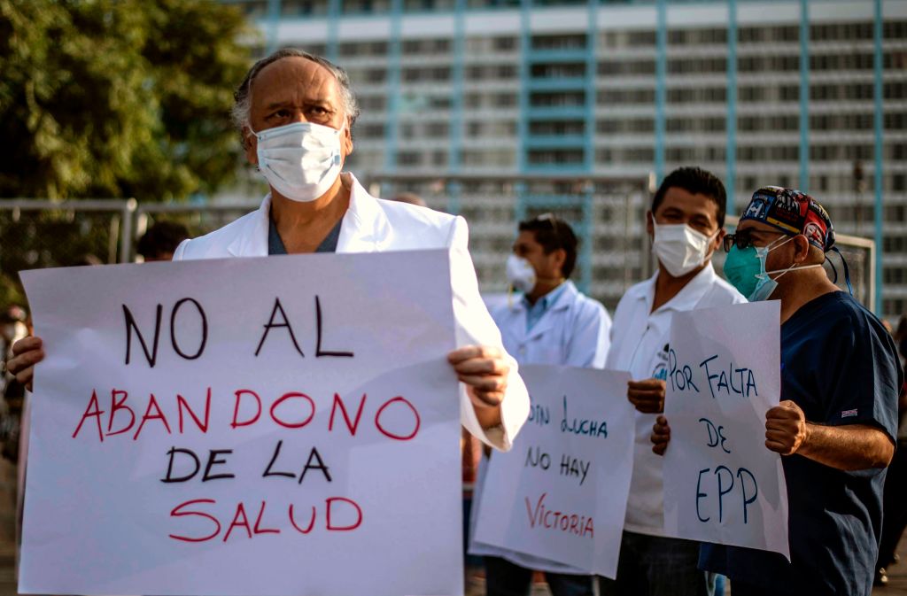 Health workers protest for the lack of security equipment demanding the resignation of Peruvian Health Minister Victor Zamora with a sign reading No to the abandonment of healthcare outside the Edgardo Rebagliati public hospital in Lima on May 13, 2020. (Ernesto Benavides – AFP/Getty Images)