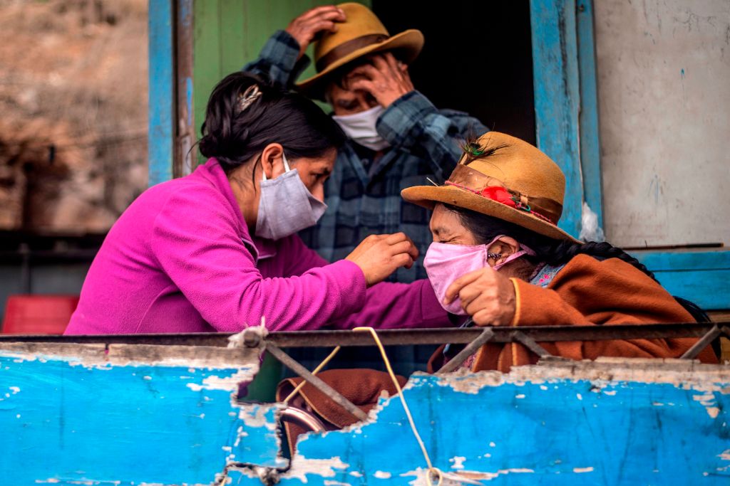 A woman arranges a her mother's face mask at their house of the Pamplona Alta section on the southern outskirts of Lima on May 28, 2020. (Ernesto Benavide – AFP/ Getty Images)